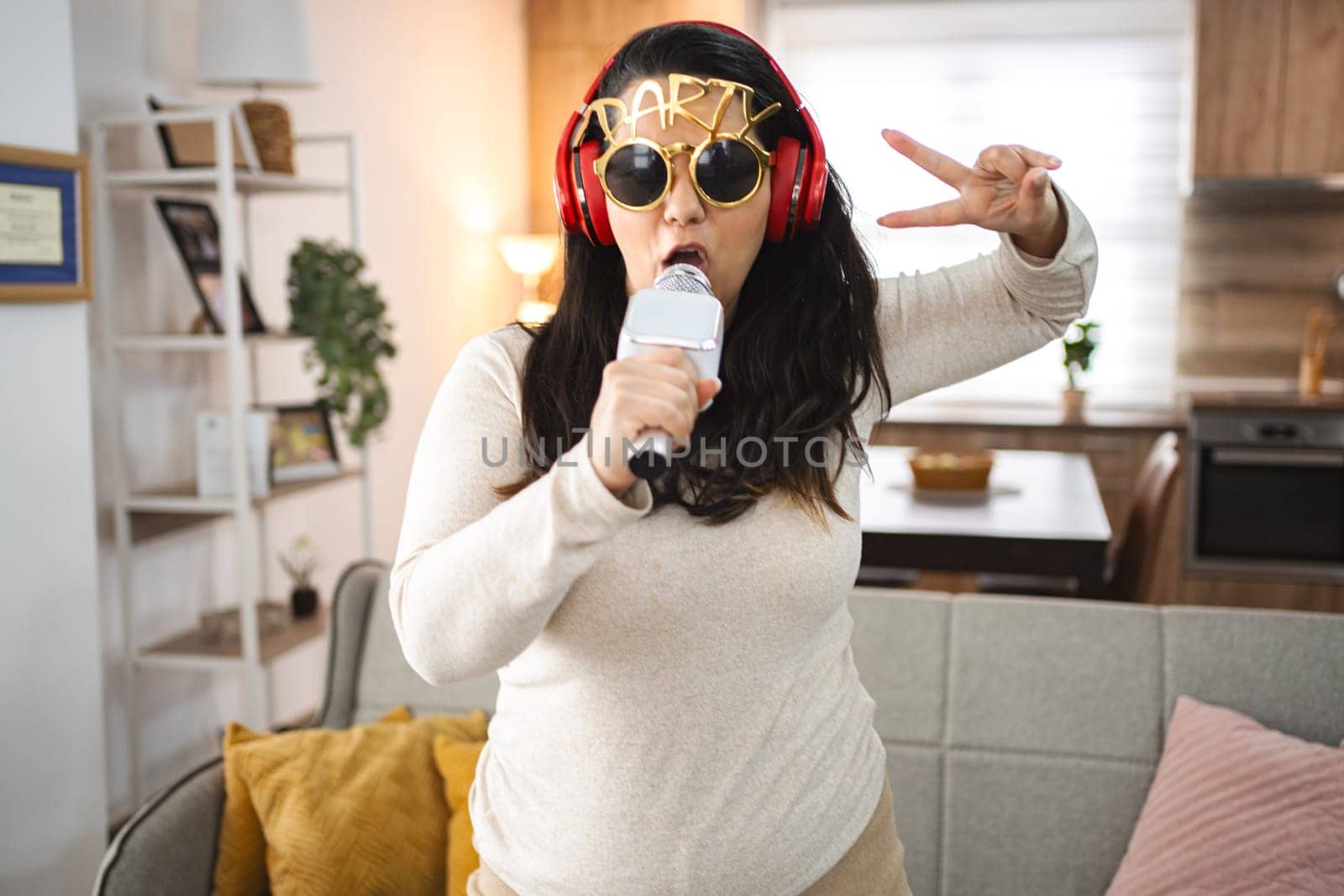 Woman with wireless headphones singing karaoke at home.