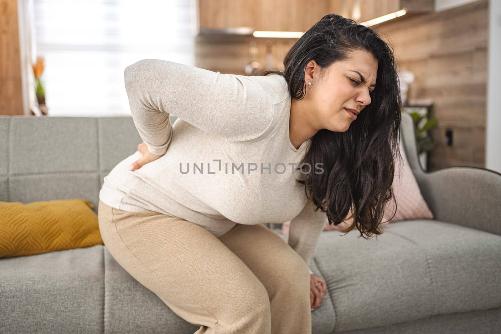 Woman suffering with back pain while at home.