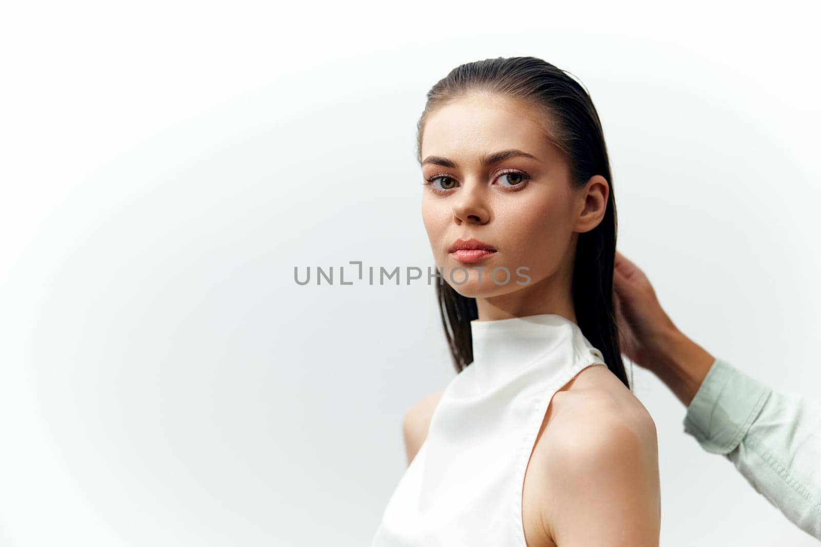 A serene young model exudes elegance with straight hair, wearing a white sleeveless top against a soft, minimalistic background. The focus on the model expression and attire creates a timeless aesthetic.