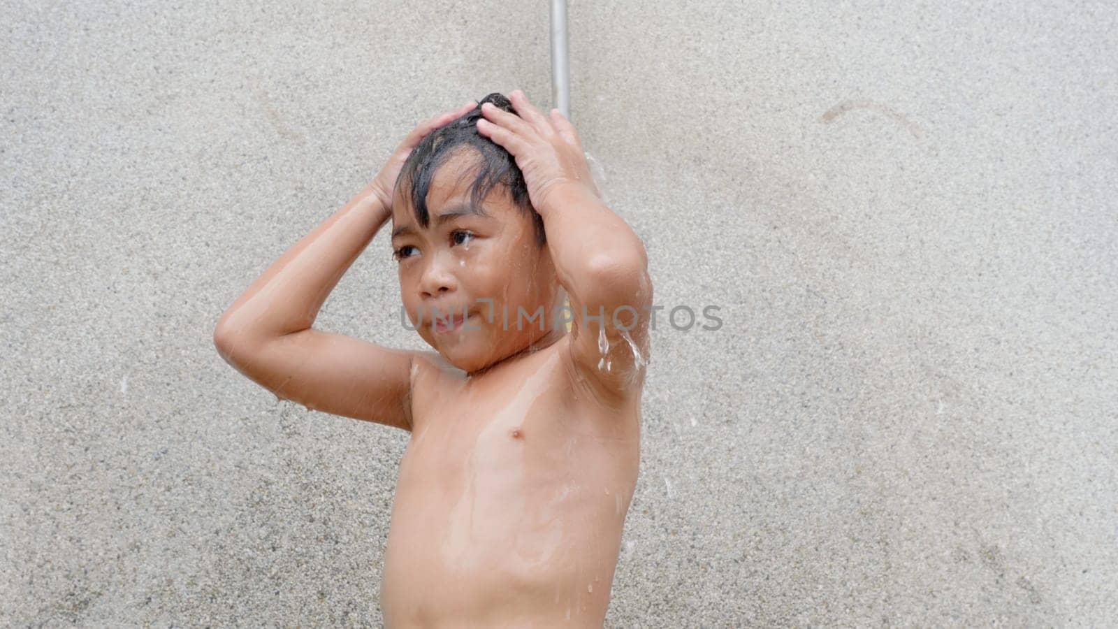 Asian child little boy taking shower at the swimming pool resort, Happy kid after swim he cleaning body refreshing and hyginic in tropical resort during family summer vacation