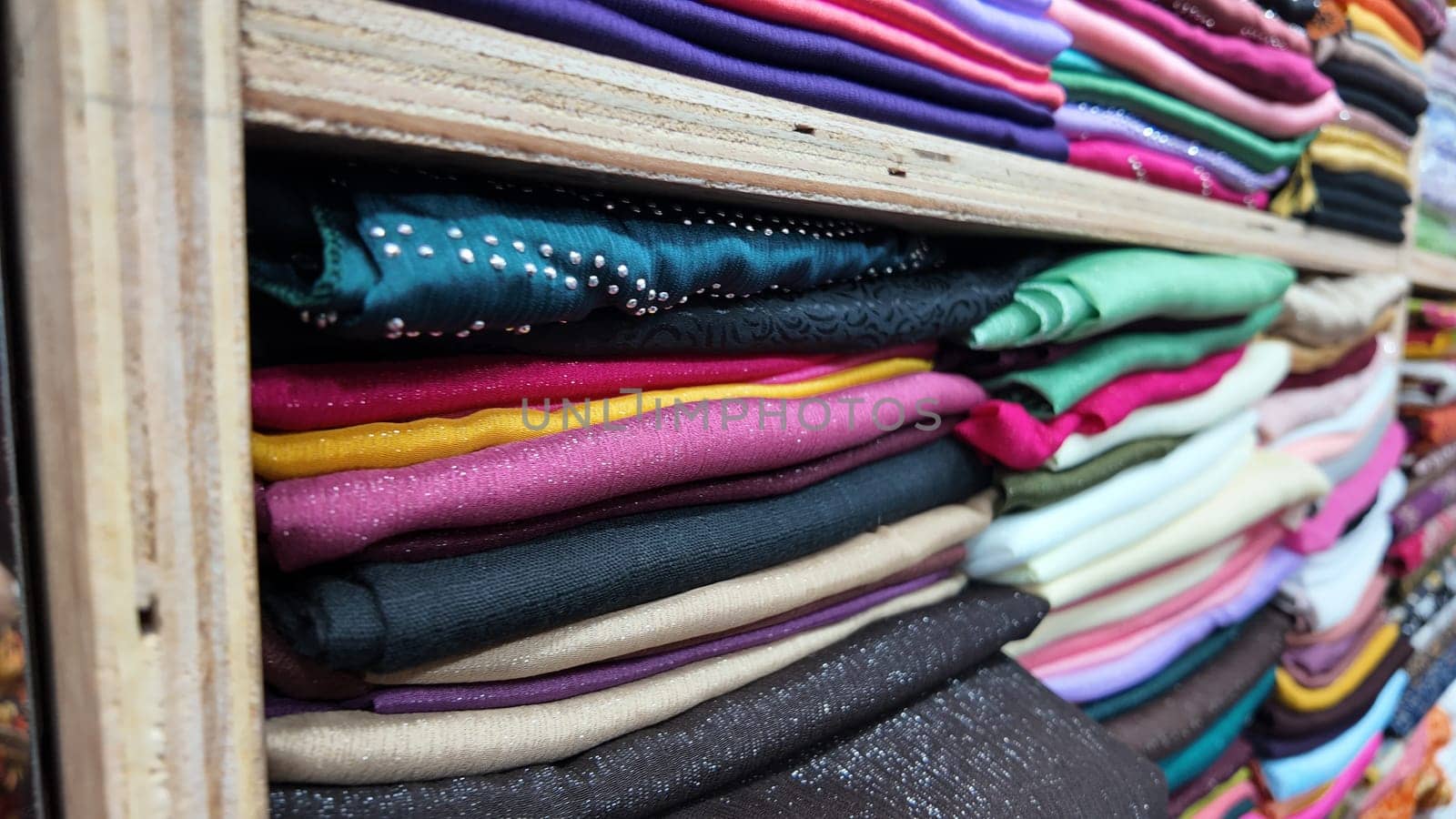 Various vibrant fabric rolls stacked neatly in a textile shop.