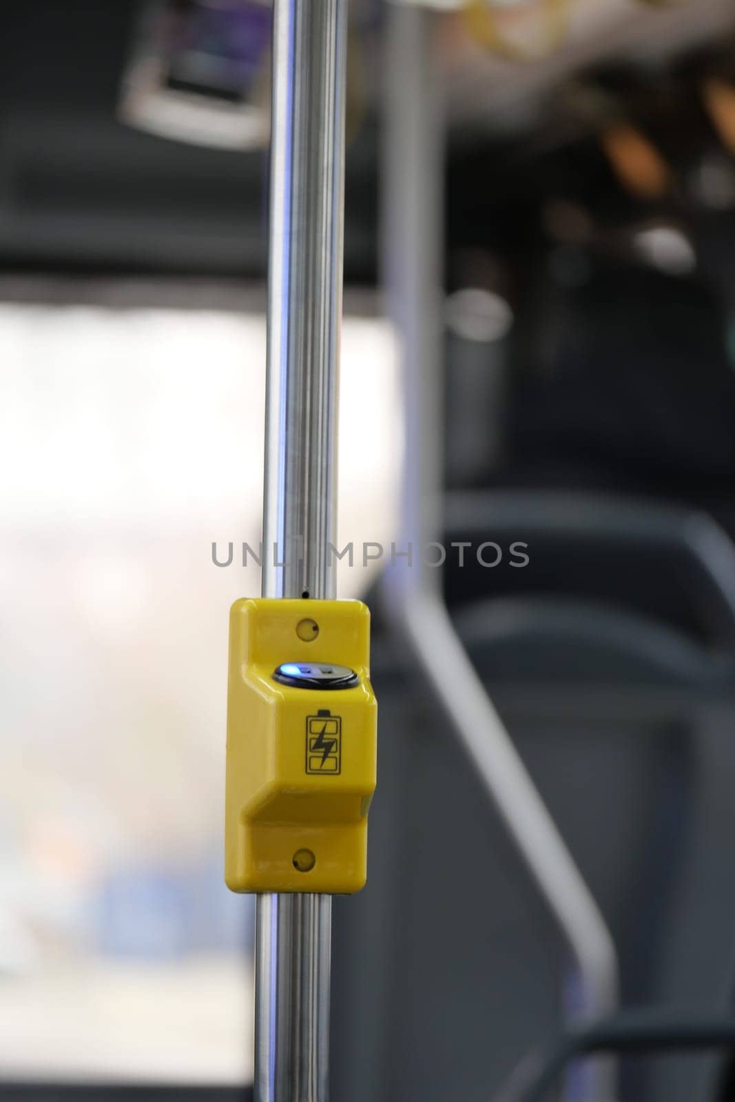 A close-up view of a yellow stop request button inside a city bus.