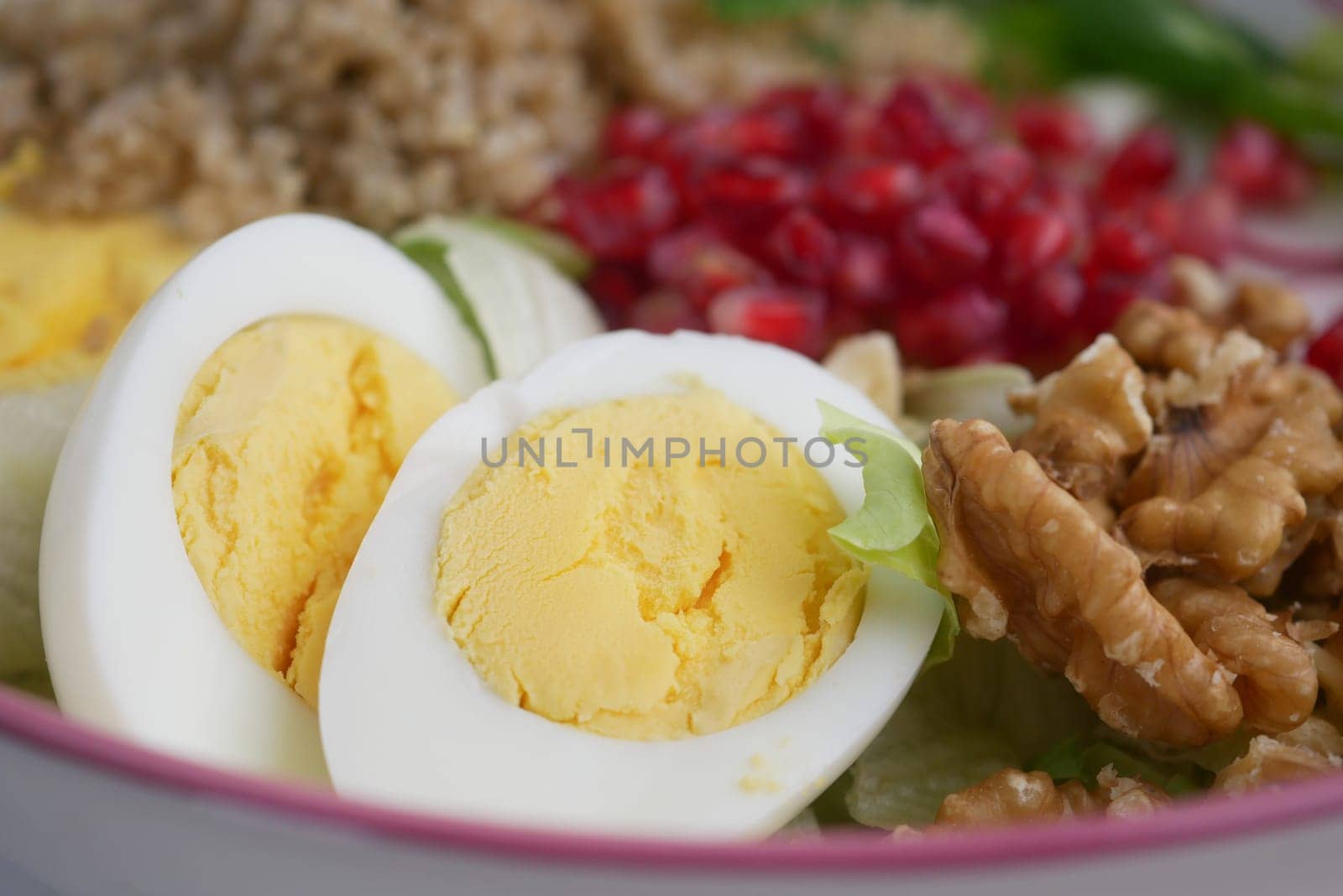 Fresh salad includes boiled eggs, pomegranate seeds, and walnuts.