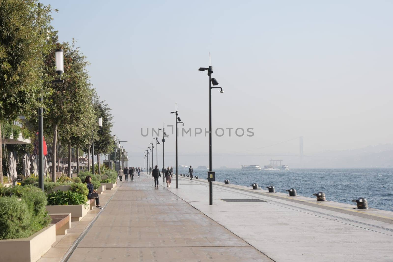 Strollers enjoy a serene morning along the waterfront near the river.