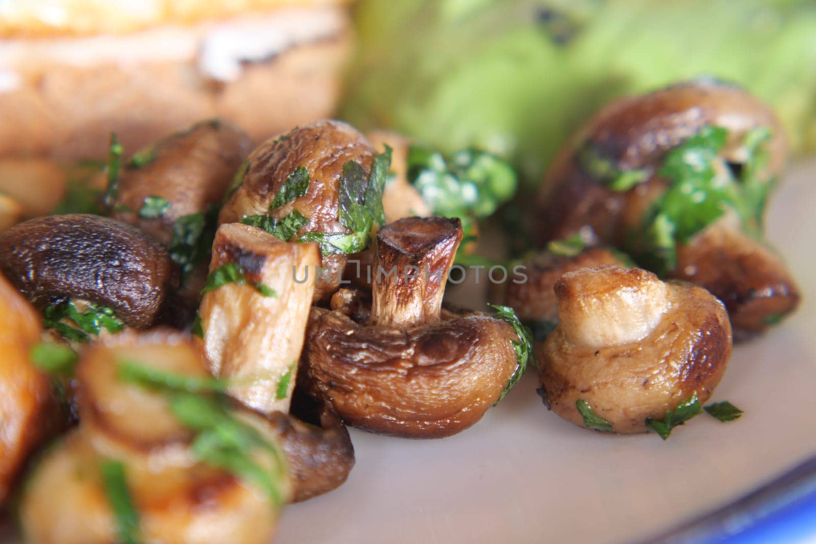 garlic mushrooms garnished with herbs on a plate.