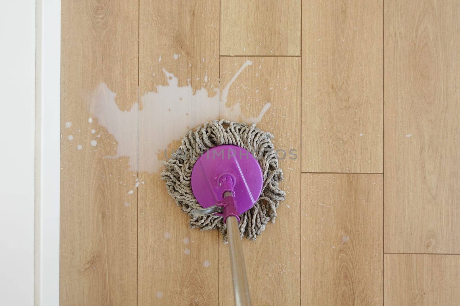 Cleaning a wooden floor with a mop and bucket in a well-lit space.
