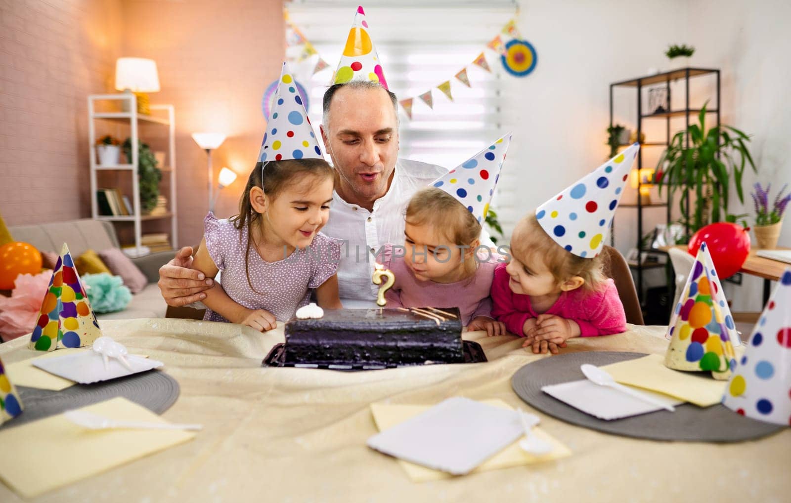 Children gather around a cake, excitedly preparing to celebrate a birthday.