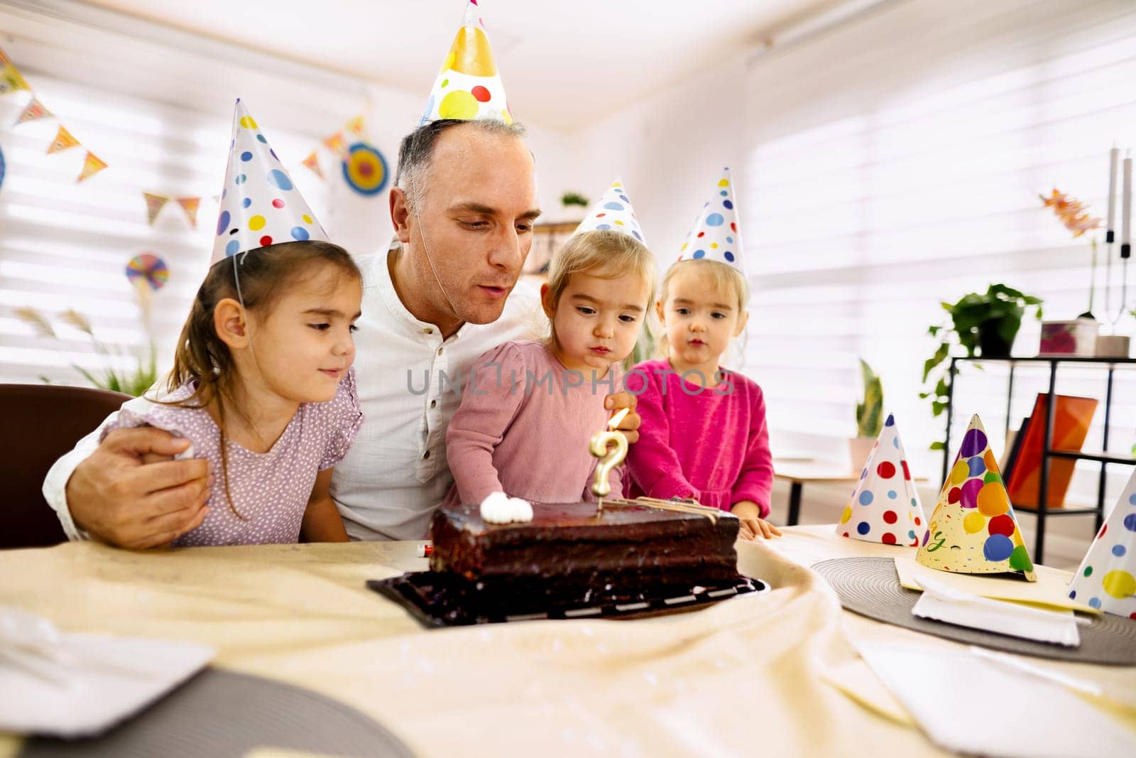 Family gathers closely to celebrate a child's birthday with cake and laughter.