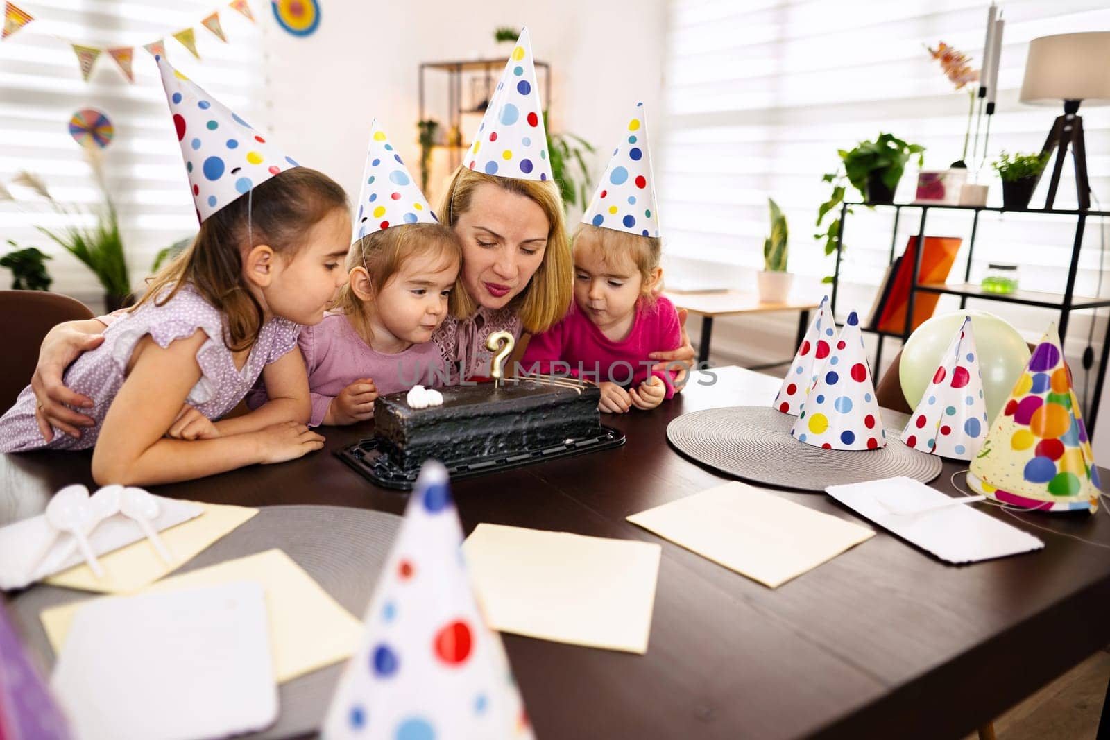 Children and an adult joyfully gather around a cake, celebrating together.