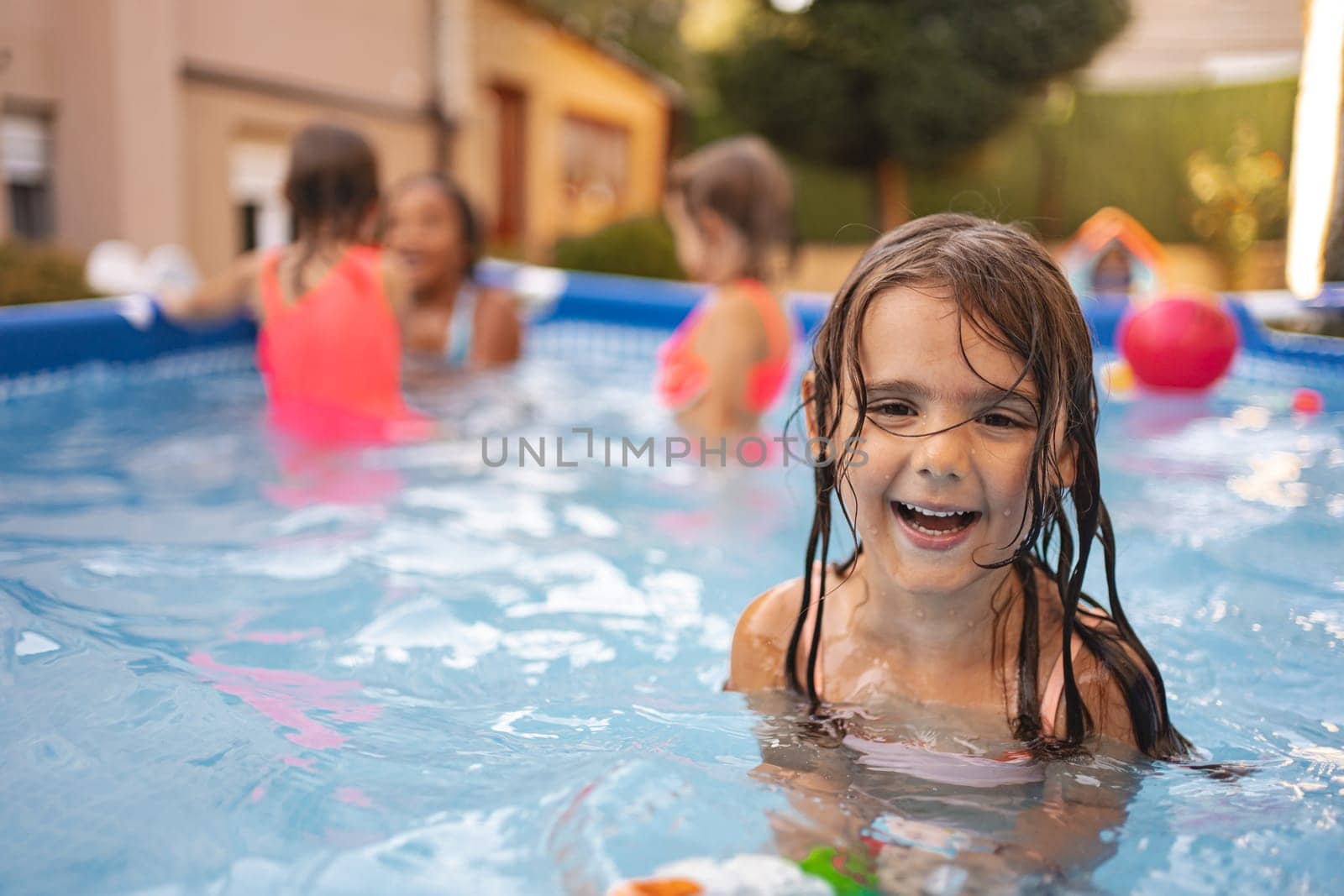A girl enjoys splashing in a pool with friends during summer fun.