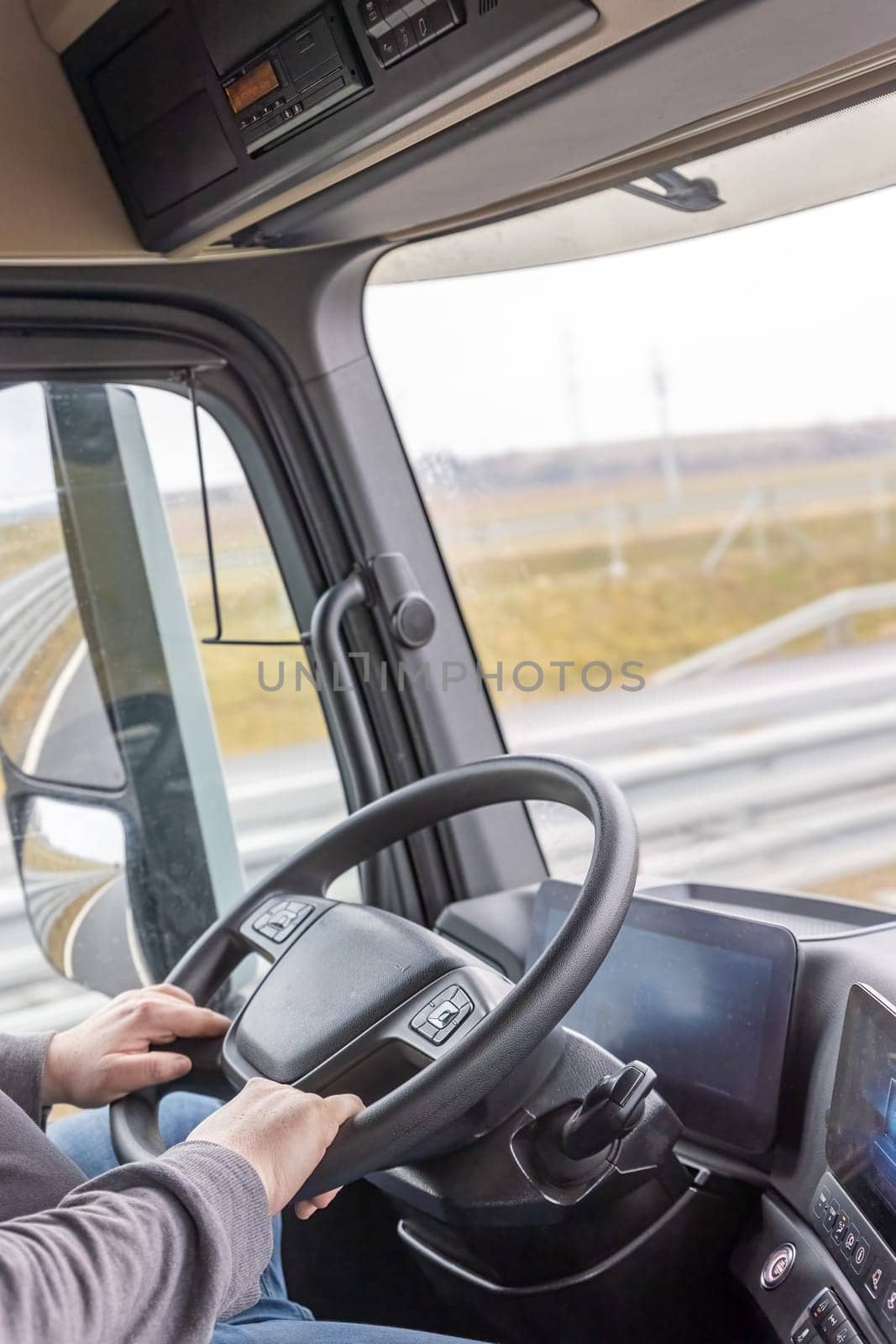 Driver inside the cab of a moving truc closeup.  Vertical. All potential trademarks are  removed. 