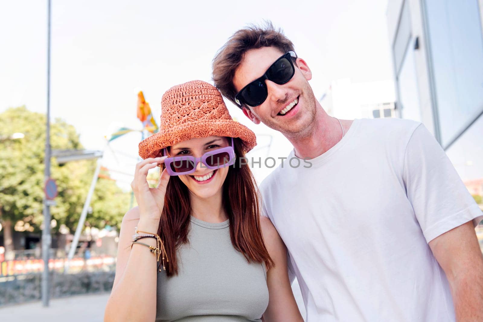 young couple smiling happy looking at camera, the woman is wearing a hat and sunglasses, concept of youth and romance, copyspace for text