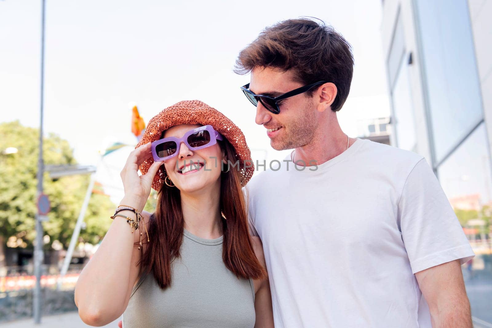young couple smiling happy during a romantic walk, the woman is wearing a hat and sunglasses, concept of youth and romance, copyspace for text