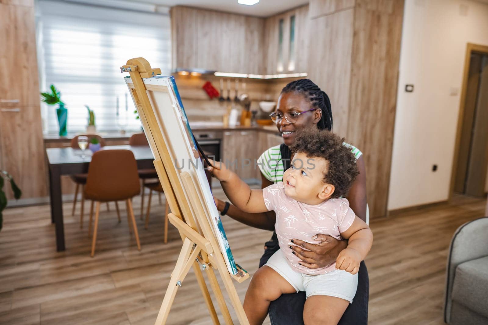 A joyful mother shares a painting moment with her delighted child.