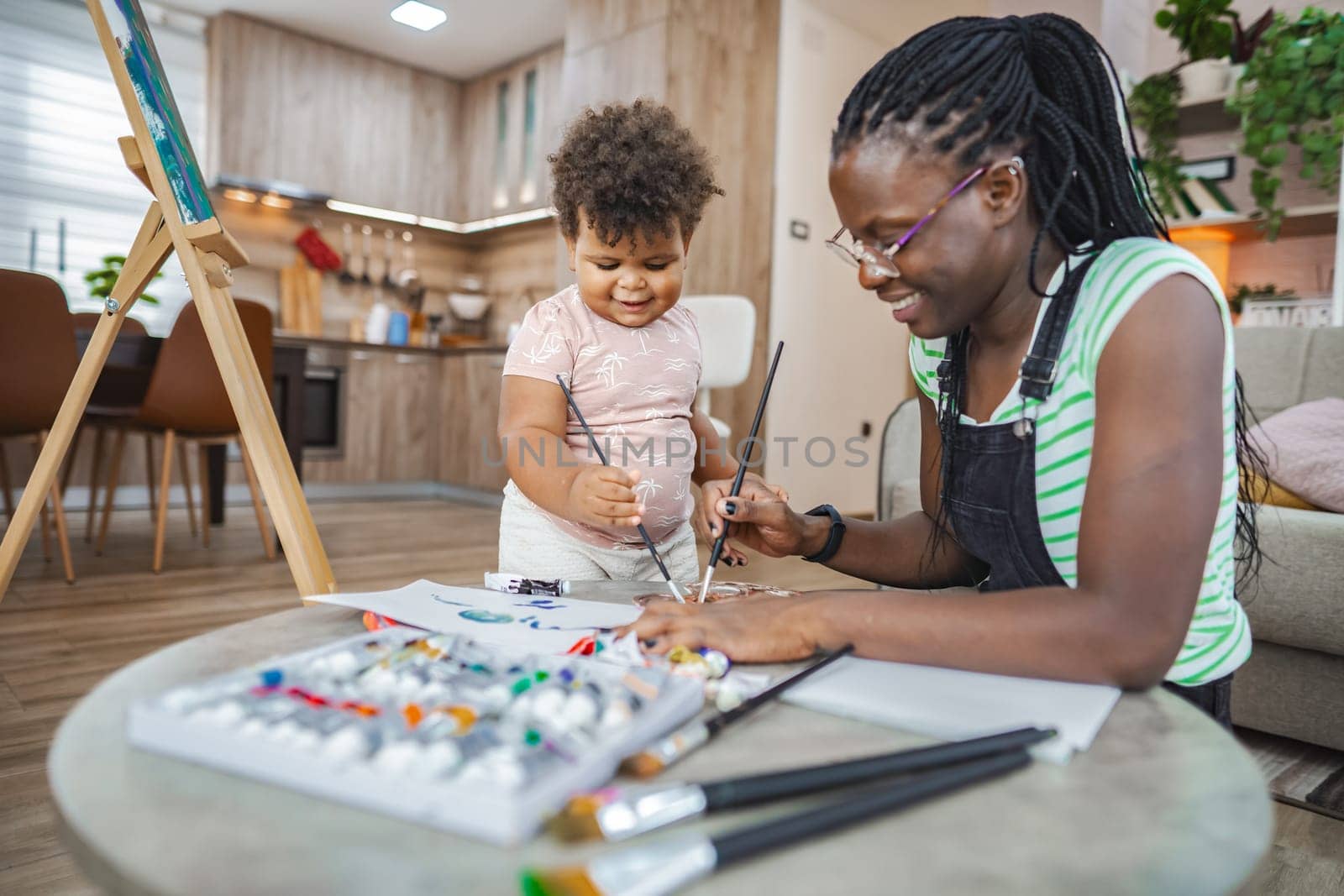 A joyful moment between mother and child as they create art at home.