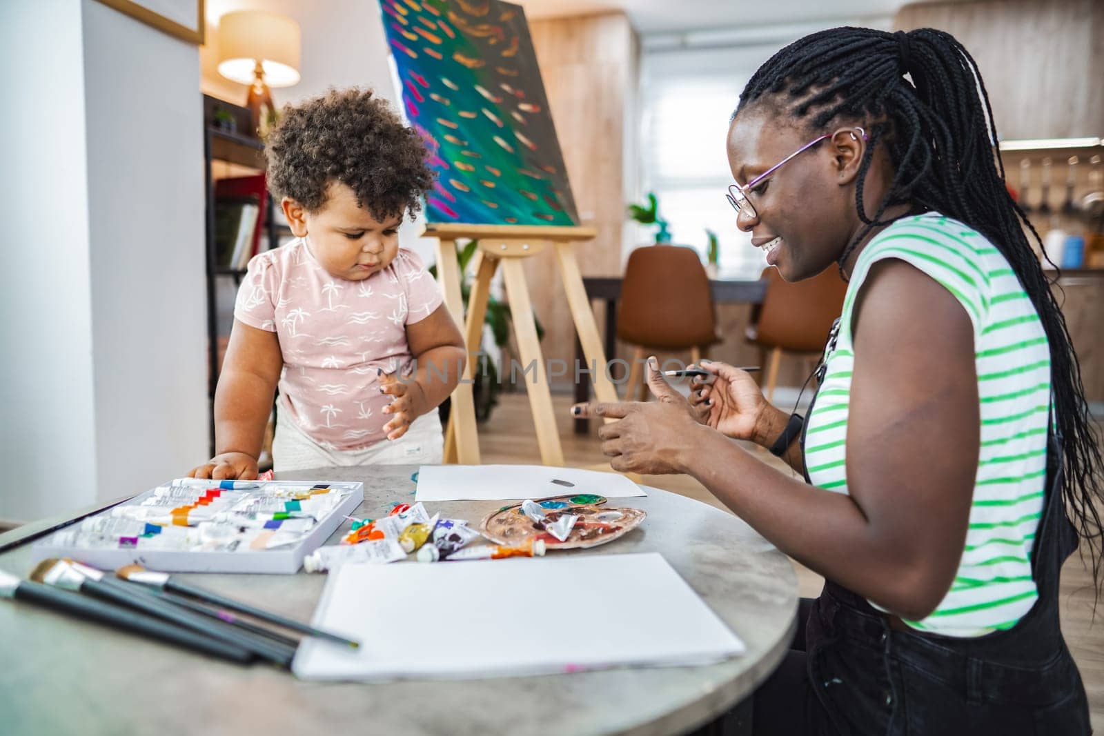 A mother teaches her child the joys of painting while creating together.