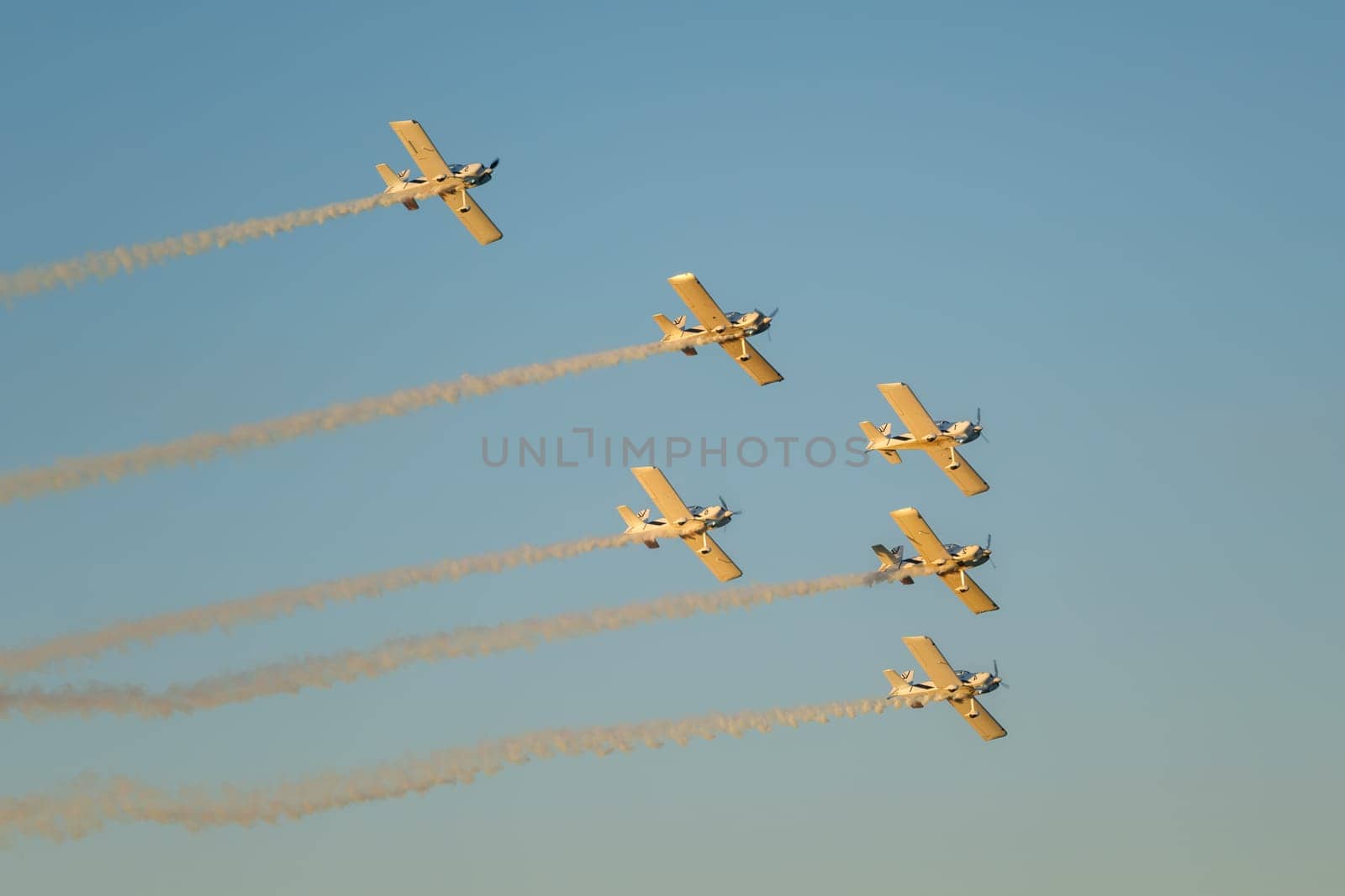 Stunt aerobatic planes performing stunts in blue sky with smoke trail. Concept of teamwork, collaboration, coordination, trust, precision, difficulty, challenge, speed, synergy