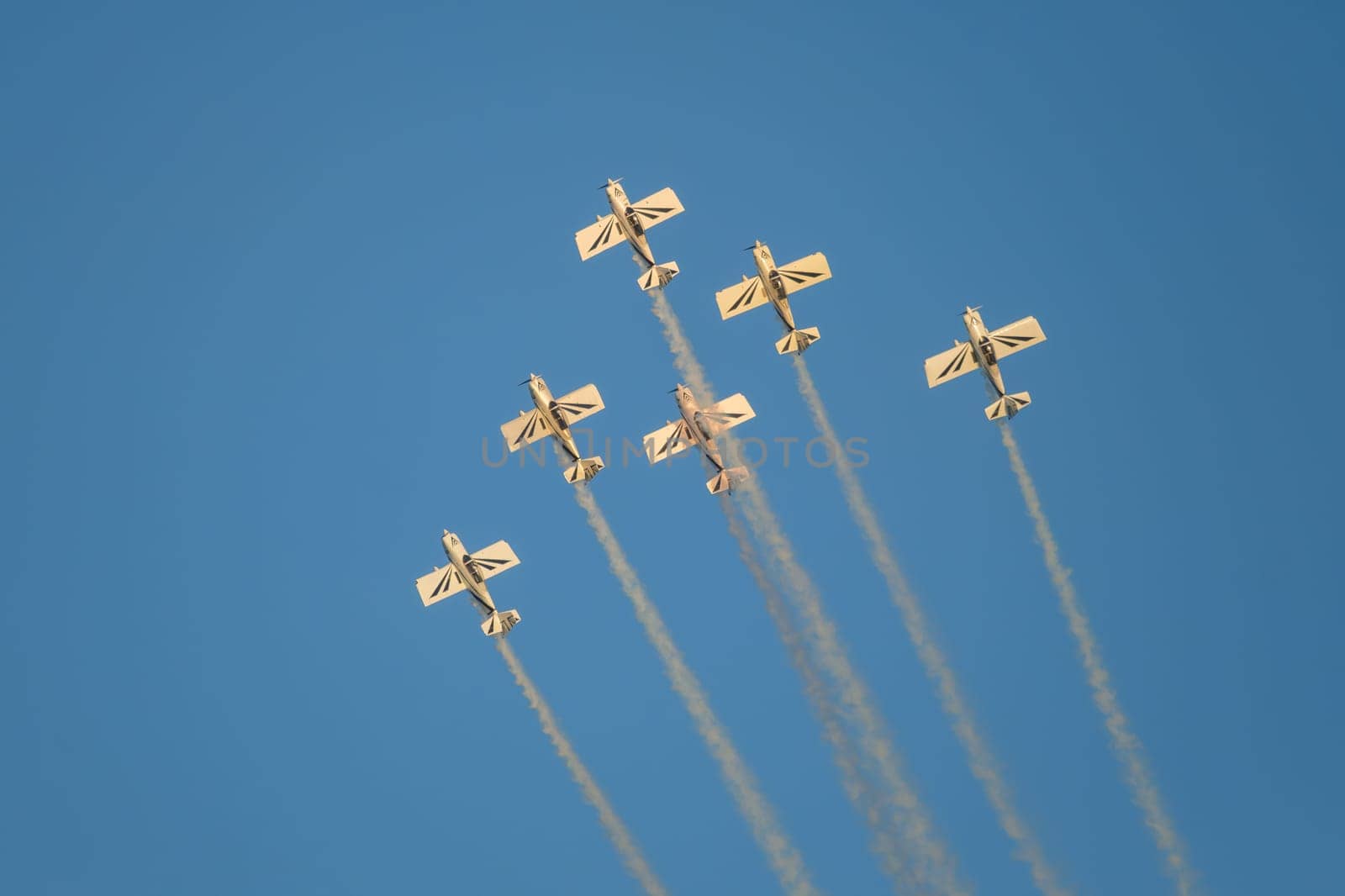 Stunt aerobatic planes performing stunts in blue sky with smoke trail. Concept of teamwork, collaboration, coordination, trust, precision, difficulty, challenge, speed, synergy