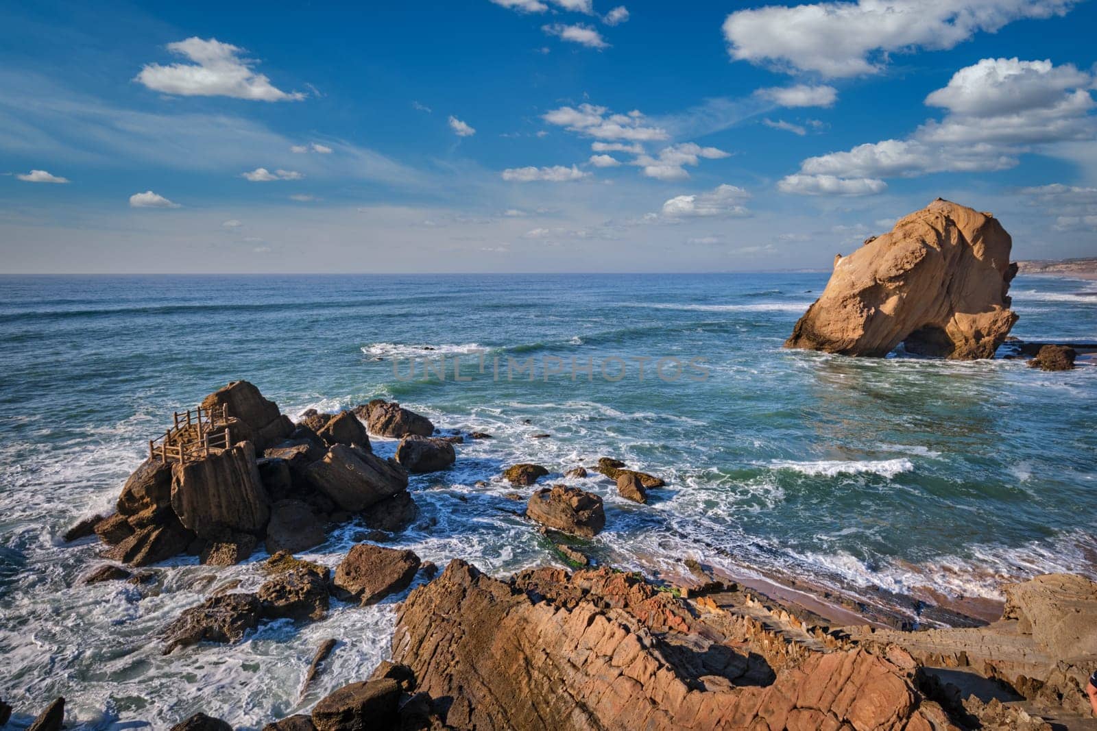 Penedo do Guincho, a large boulder rock arch at Praia da Santa Cruz, Portugal, with ocean waves and sandy beach