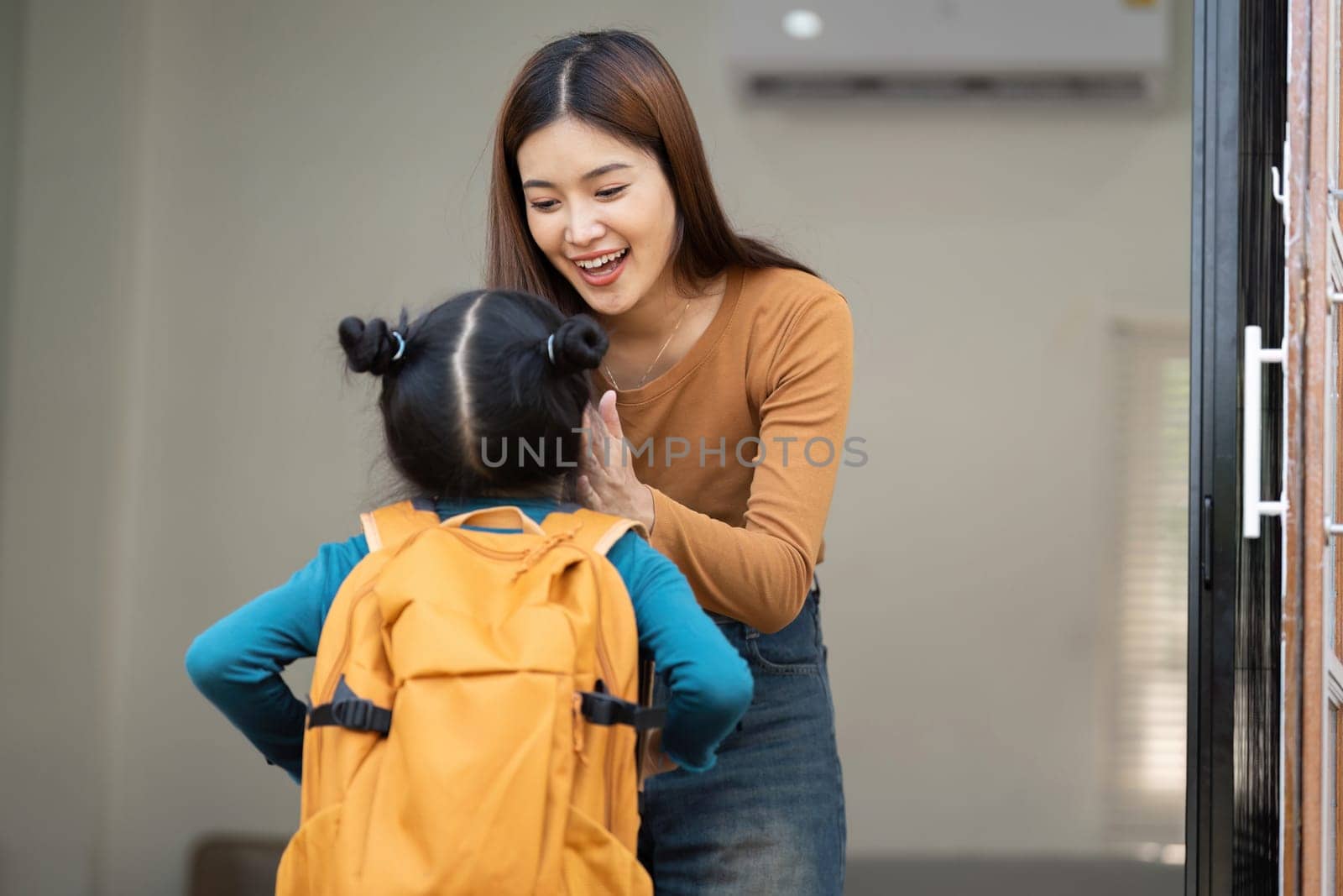 A loving mother greets her daughter with a warm smile while the girl, clad in her school outfit, appears excited about the day ahead.