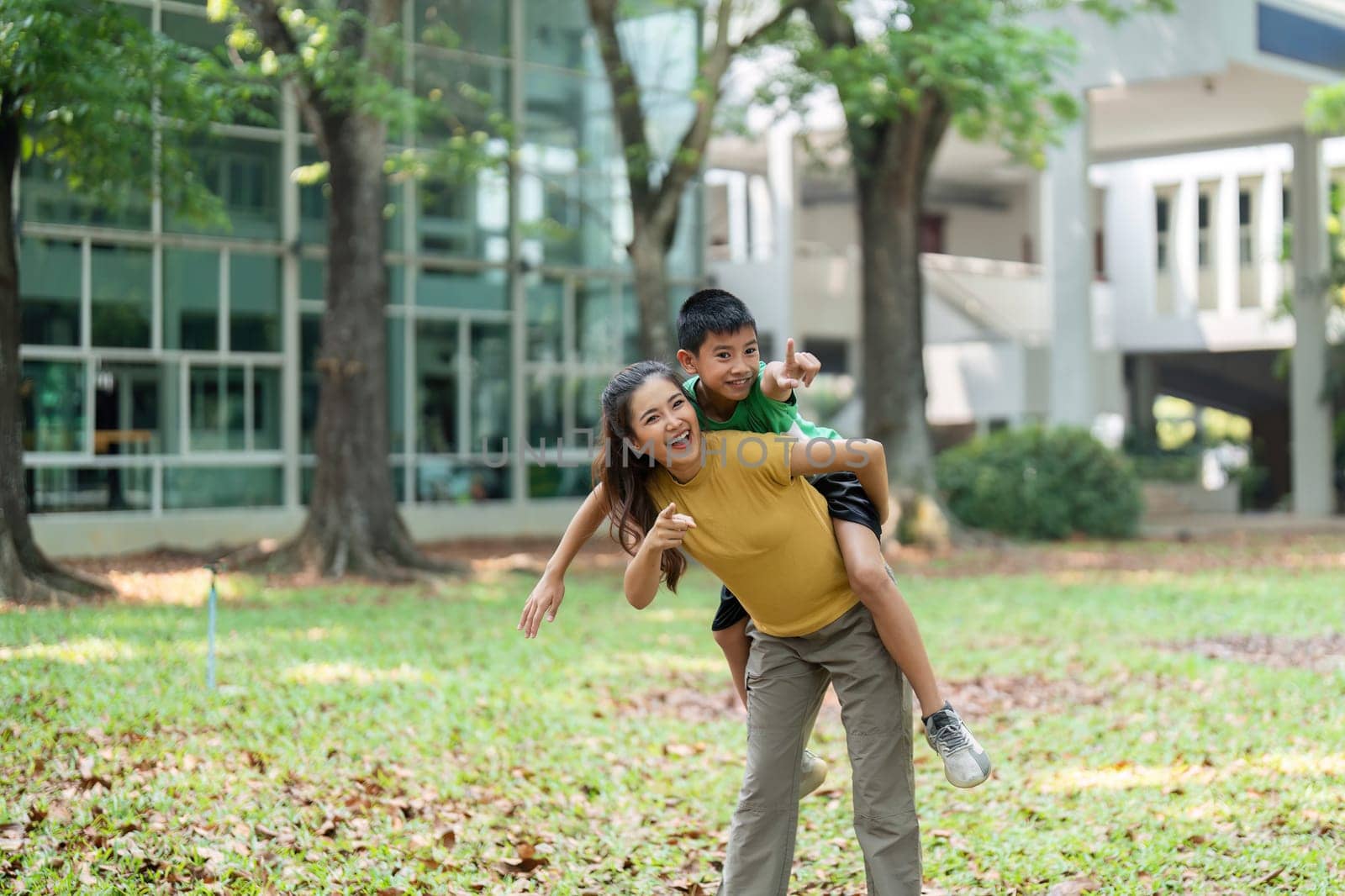 The image captures joyful interaction as a girl gives a boy a piggyback ride, both enjoying the moment in a beautiful outdoor setting.