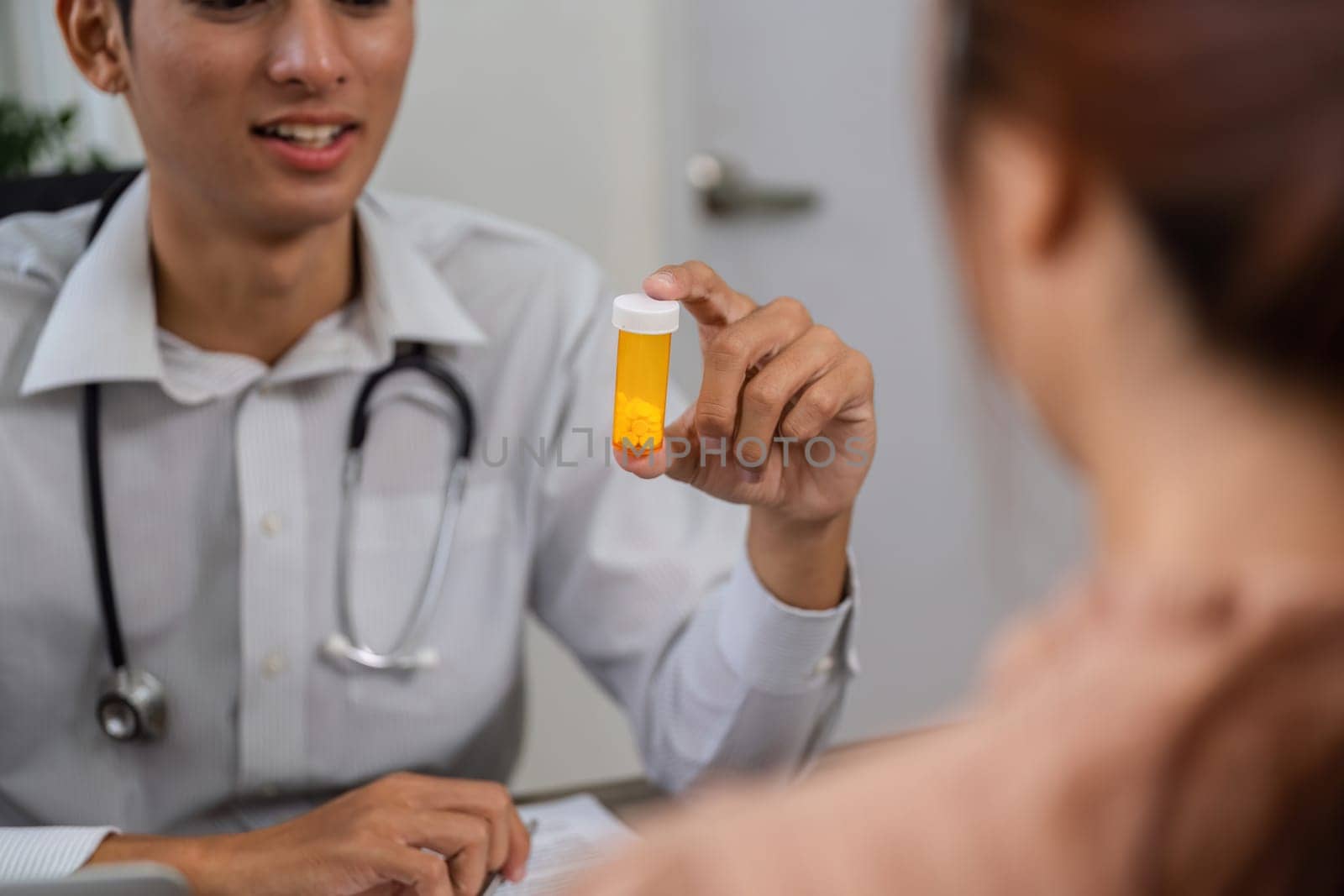 During a consultation, a doctor presents a pill bottle to a patient, ensuring they understand the purpose of their medication and treatment.