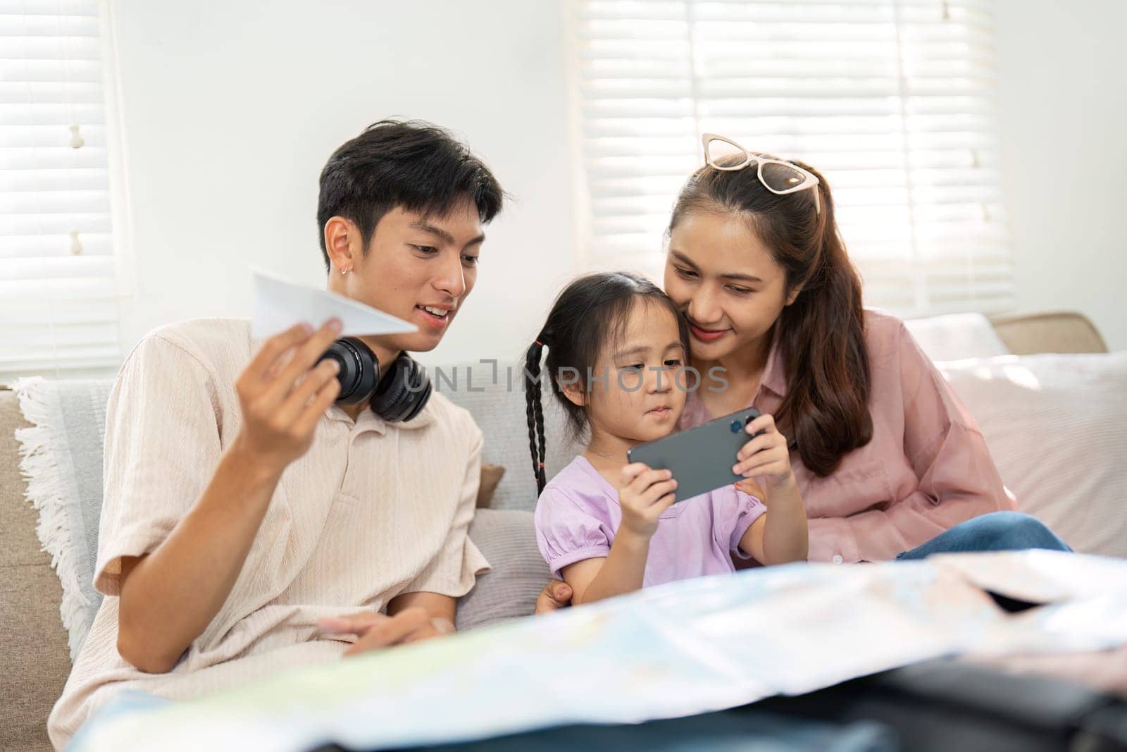 Engaged in a creative activity, a family sits together as their daughter learns through a smartphone, reinforcing the value of technology in parenting.