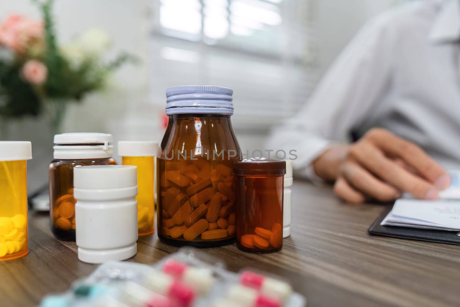 Various medication bottles are displayed on a desk, reflecting important pharmaceutical care and management in a health consultation context.