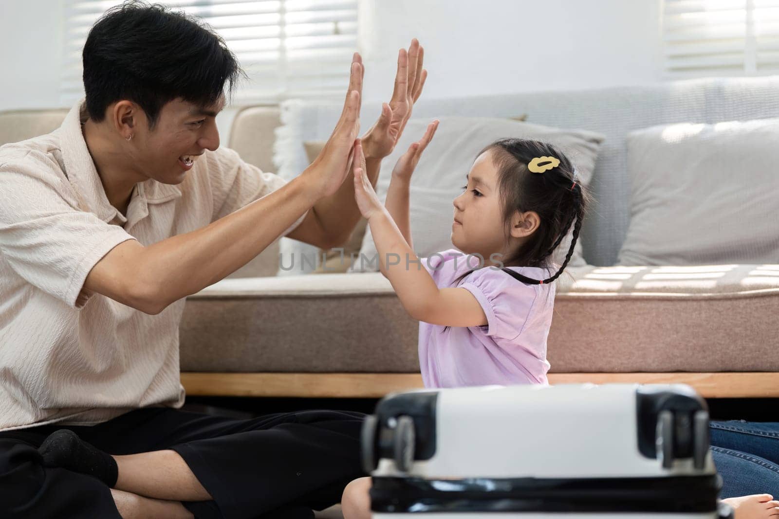 Amidst travel preparations, a father and daughter enjoy quality time together, playfully interacting as they prepare for their trip.