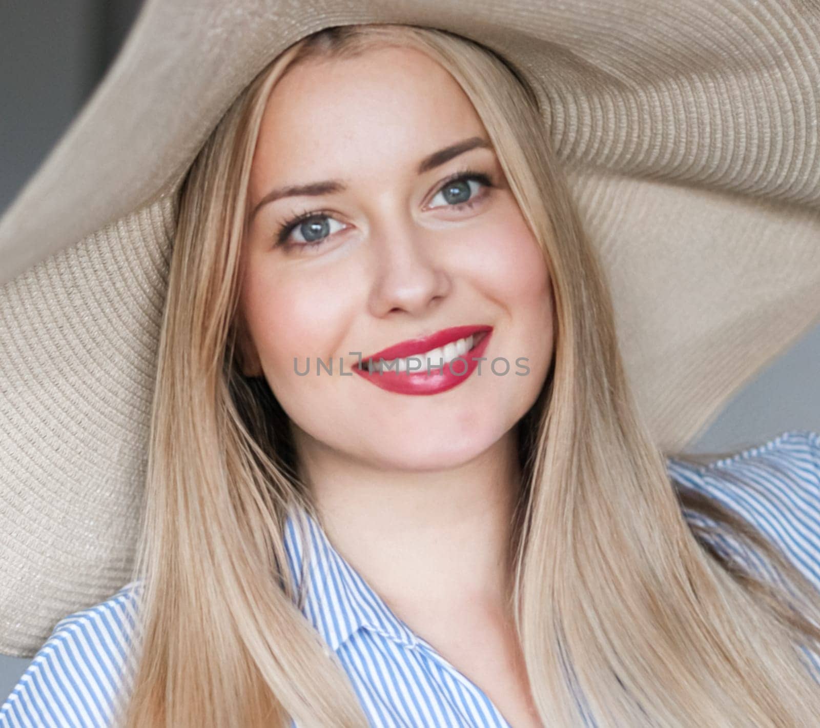 Woman, fashion and summer country charm, blonde beauty and elegance in wide brimmed beach hat. Feminine allure, timeless style and graceful glow. Smile, straw hat and blue striped blouse, natural lighting and effortless charm, fashion look idea