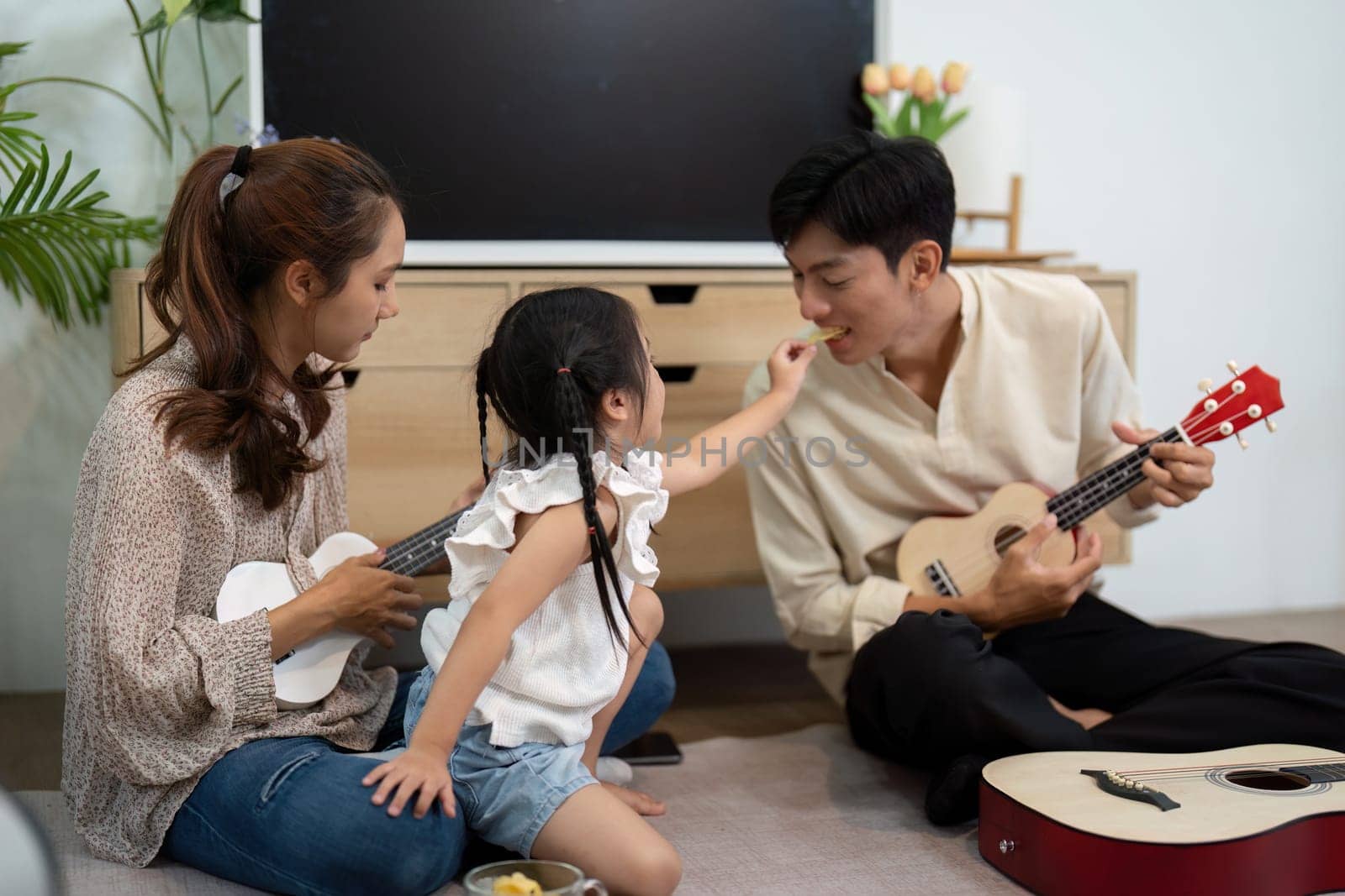 A delightful scene where a little girl playfully engages with her parents during a musical session, highlighting joy and family connection.