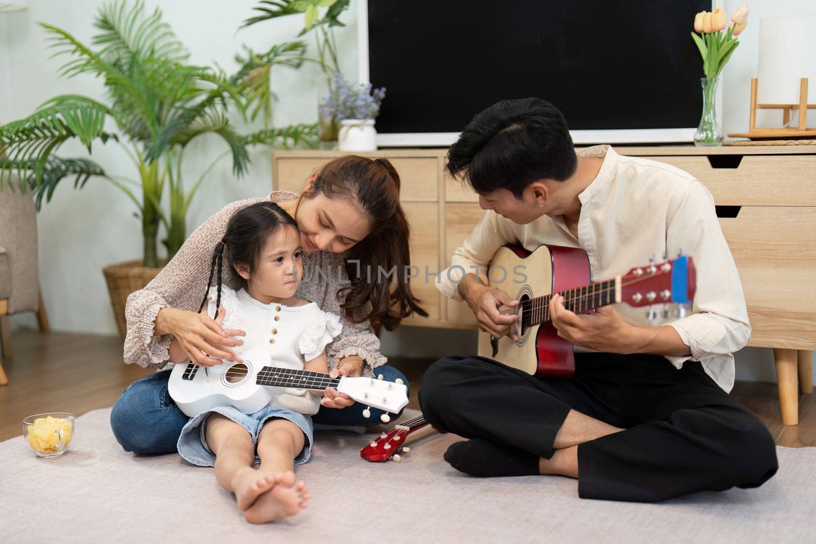 In a delightful family scene, a mother and her daughter play together, fostering creativity and joy through music in a cozy home environment.