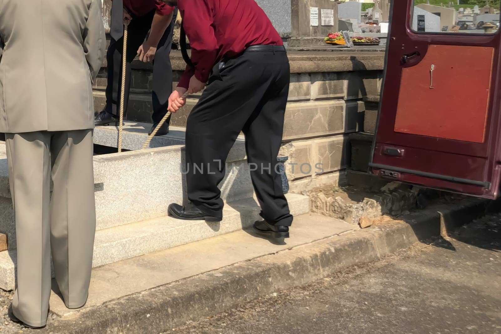Porters lower the coffin into the grave in the cemetery