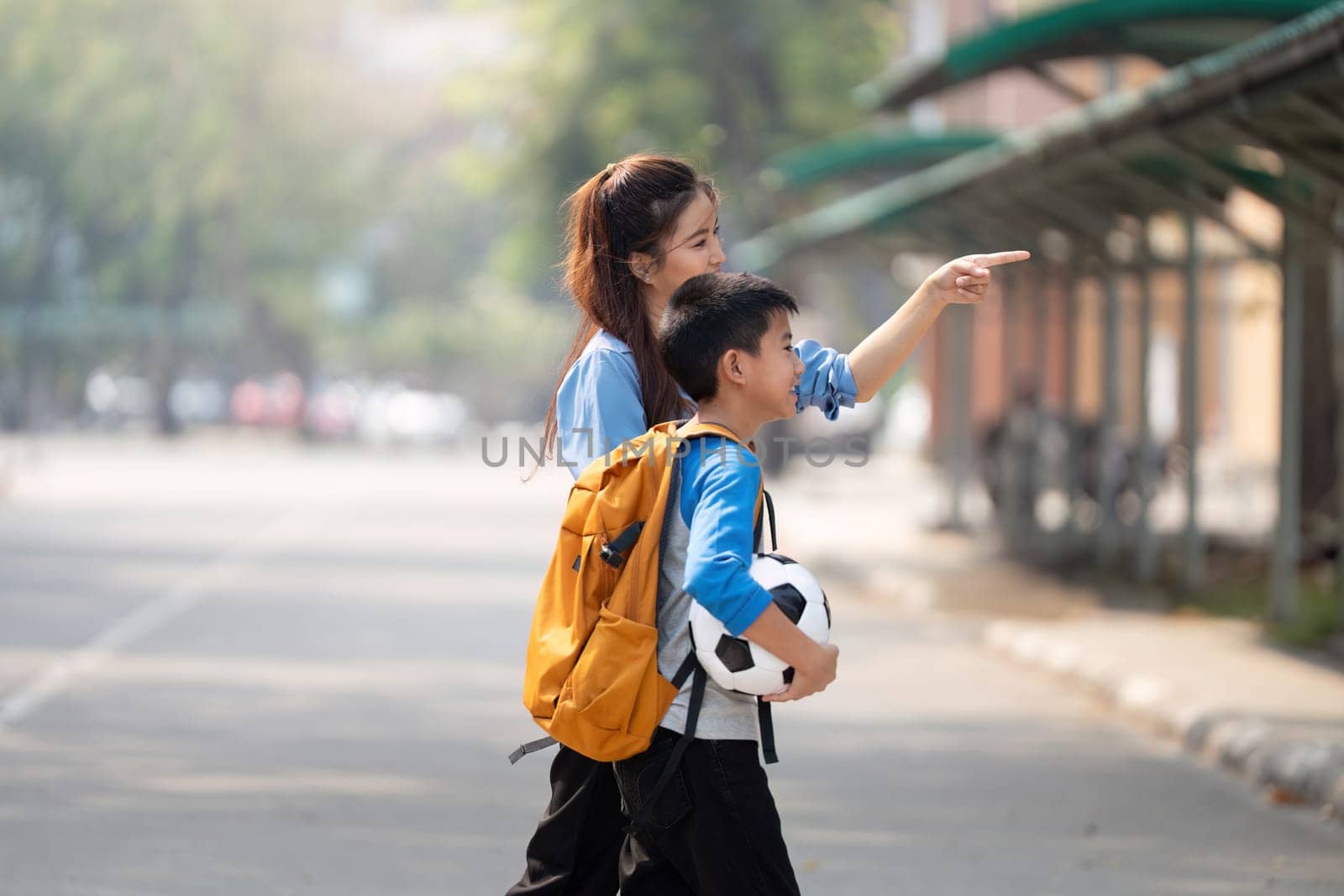 A mother and her son are walking home from school, with the boy holding a soccer ball. They share a moment of joy and exploration, emphasizing parental support and childhood excitement.