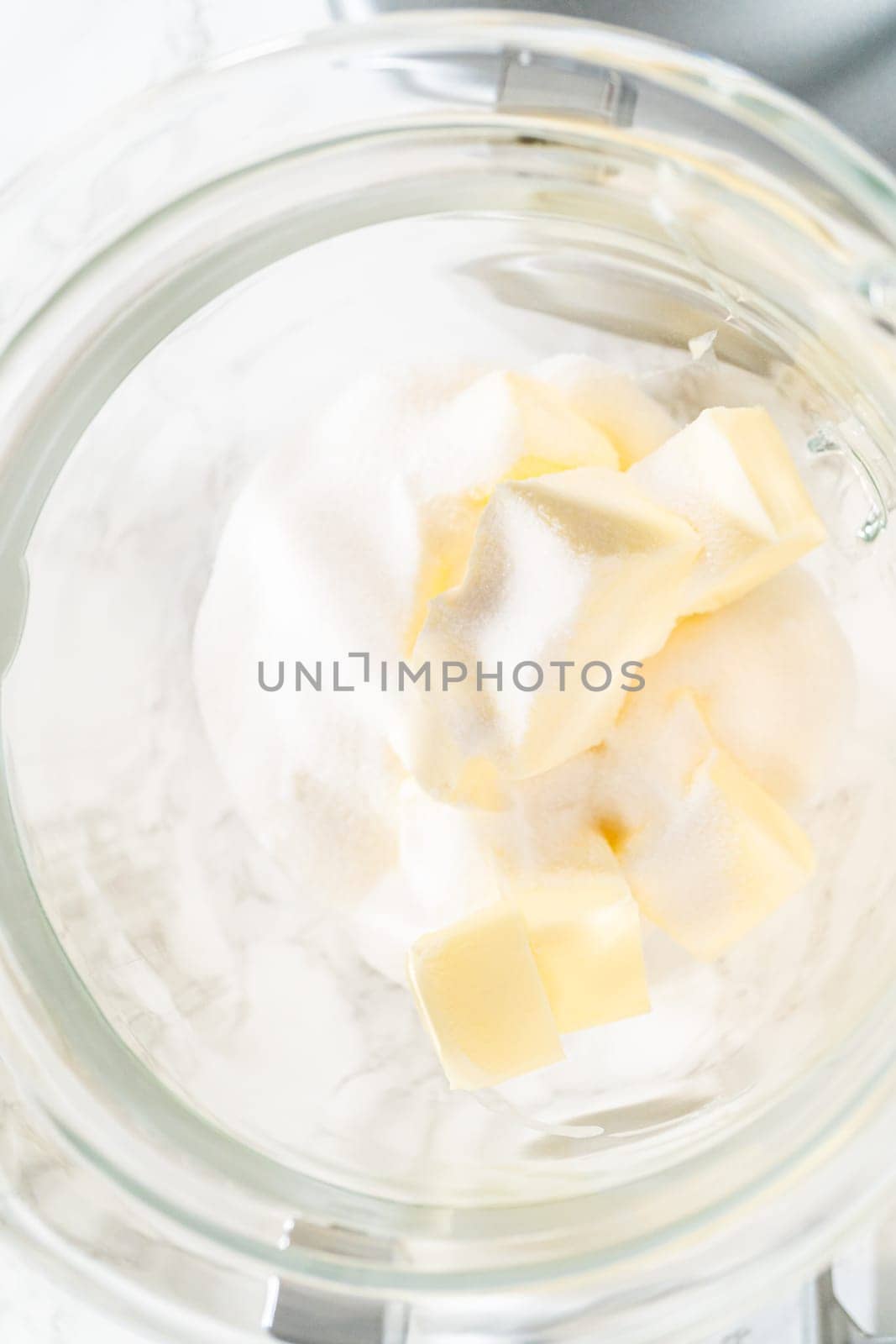 Top view of sugar and butter cubes in a mixing bowl, ready to be creamed together as the first step in making Classic Sugar Cookie Dough. The ingredients are positioned for blending, a key step for creating a smooth cookie base.