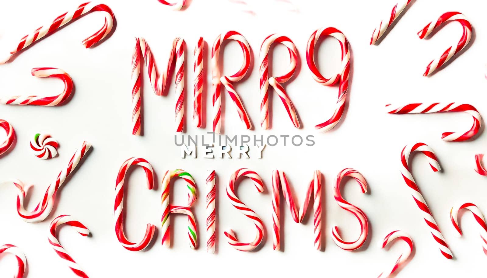 Two images of candy canes arranged to spell out "Merry Christmas" on a flat white background. The red and white striped candy canes form a festive and colorful holiday message, adding a cheerful and playful feel to the scene.