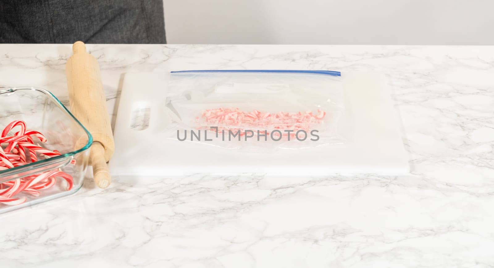 Castle Rock, Colorado, USA-November 26, 2024-Focused view of a rolling pin placed next to a ziplock bag filled with partially crushed candy canes, set on a marble surface for baking preparation