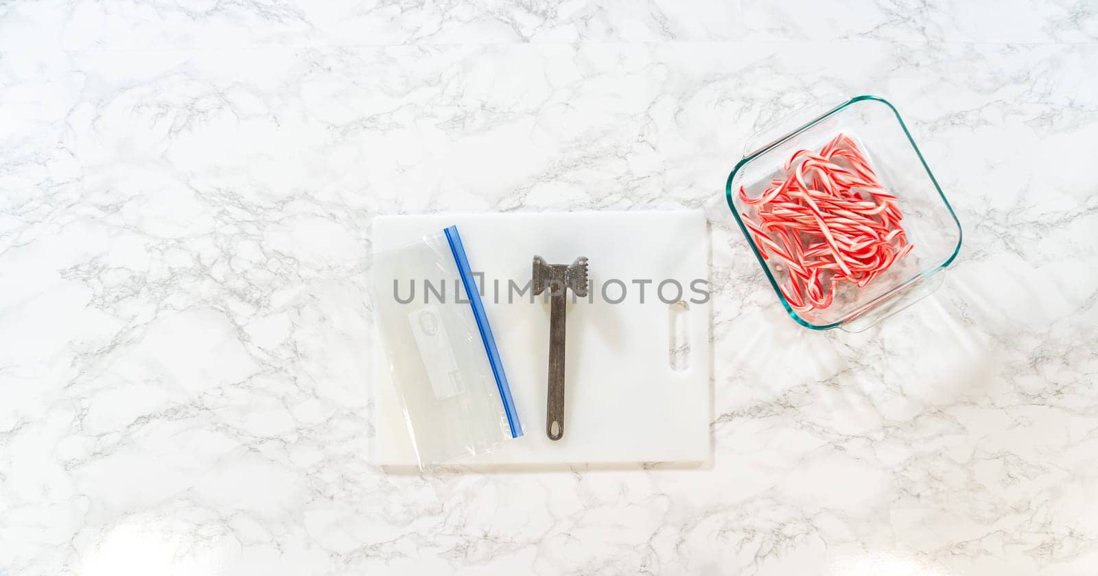 Castle Rock, Colorado, USA-November 26, 2024-Tools for crushing candy canes displayed on a marble surface, including a small mallet, plastic bag with crushed candy, and candy canes in a container