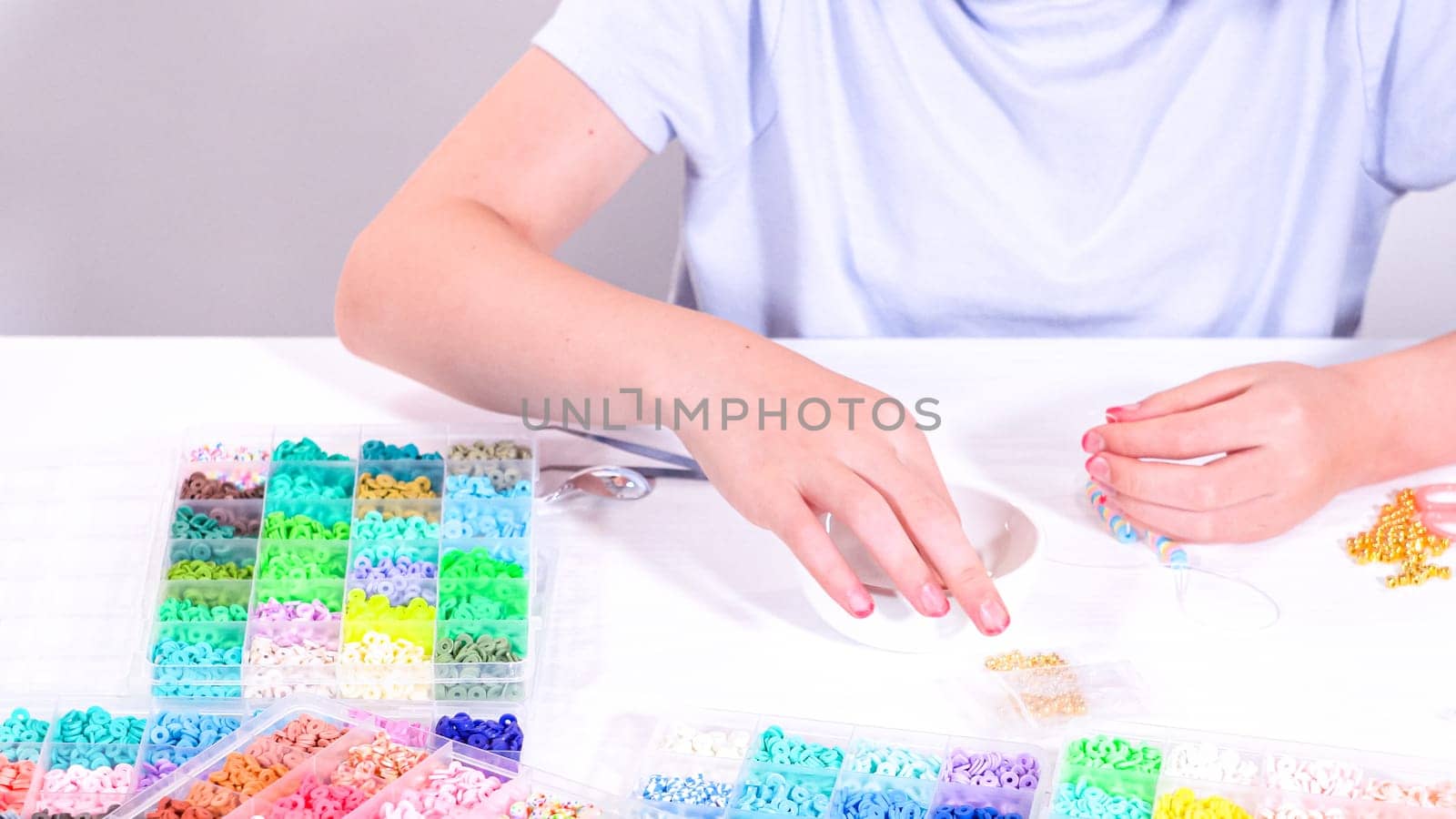 Delicate fingers of a young girl navigate through a treasure trove of bright, multicolored beads, each compartment revealing a new hue to choose from.