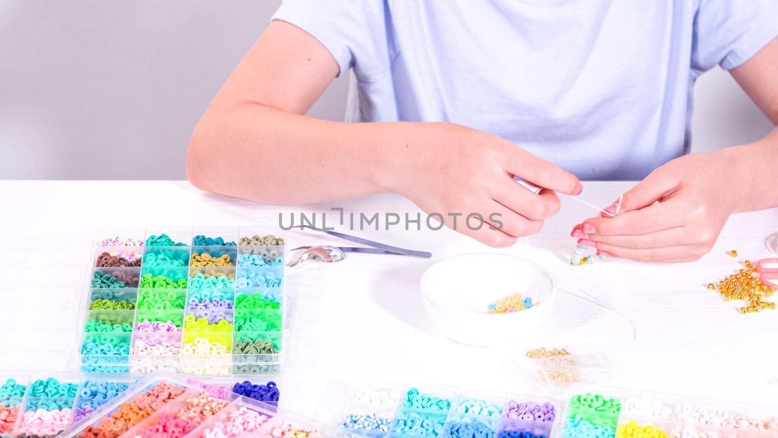 Delicate fingers of a young girl navigate through a treasure trove of bright, multicolored beads, each compartment revealing a new hue to choose from.