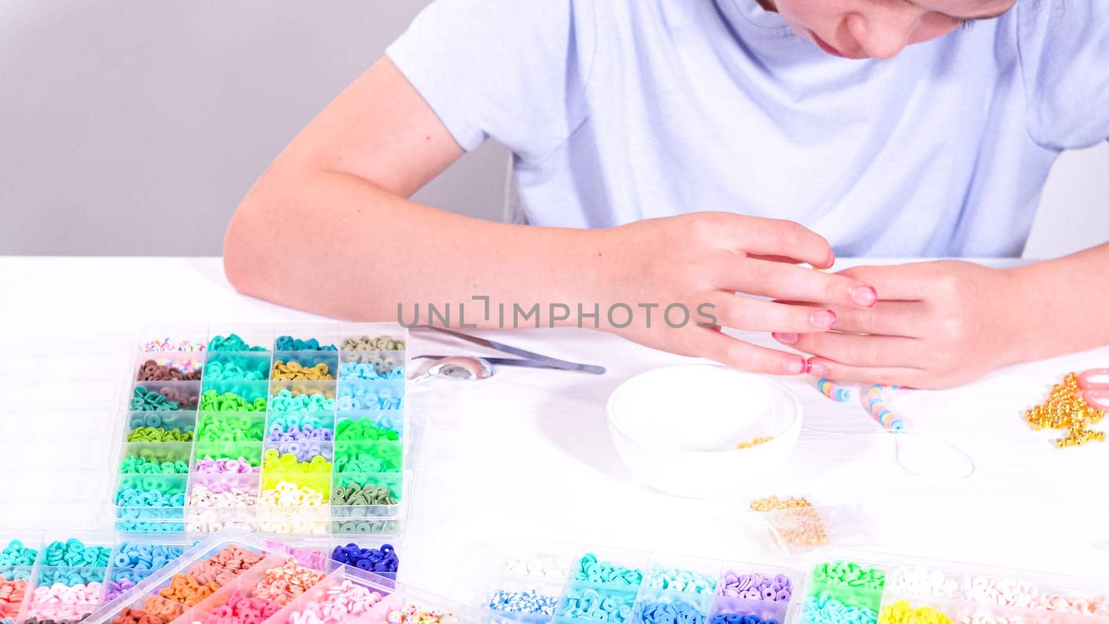 Delicate fingers of a young girl navigate through a treasure trove of bright, multicolored beads, each compartment revealing a new hue to choose from.