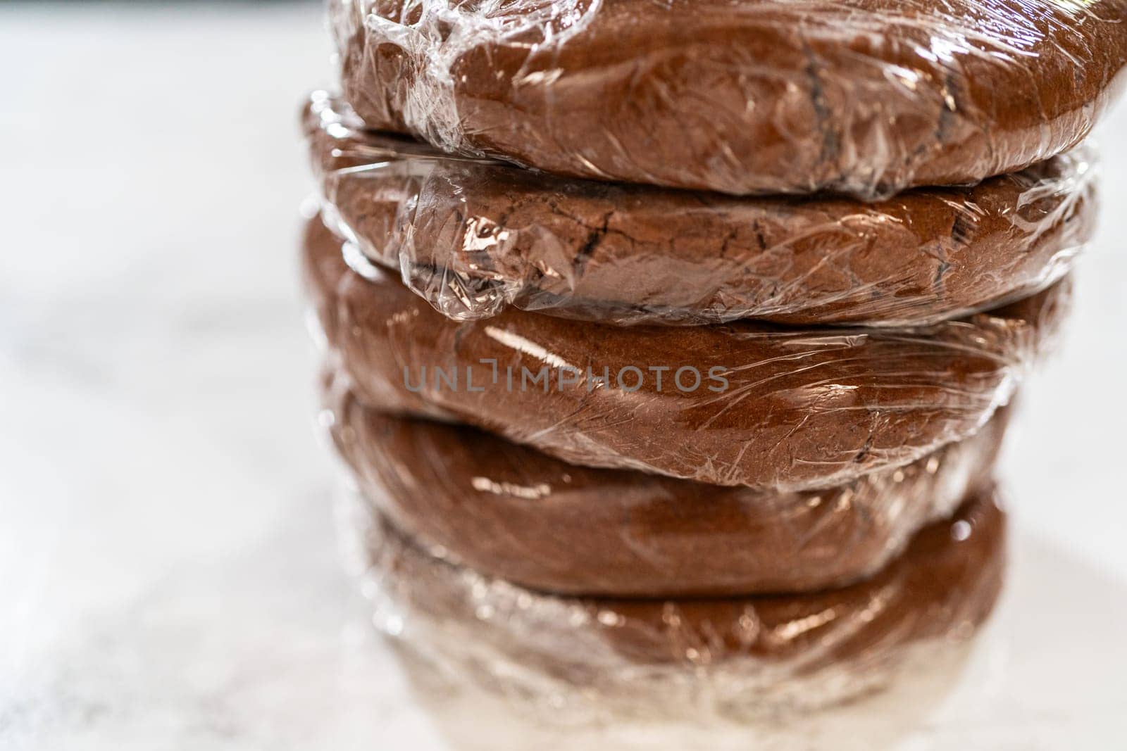 Multiple wrapped dough disks stacked, ready for refrigeration, setting up for batch baking later.