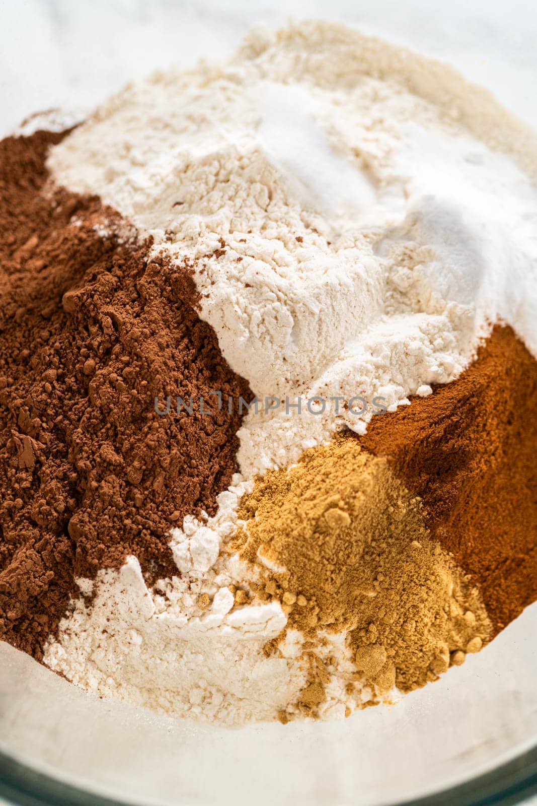 Close-up of a mixing bowl with cocoa powder, flour, ginger, and cinnamon for the Chocolate Ginger Sugar Cookie Dough, showing the spices and dry ingredients ready for mixing.