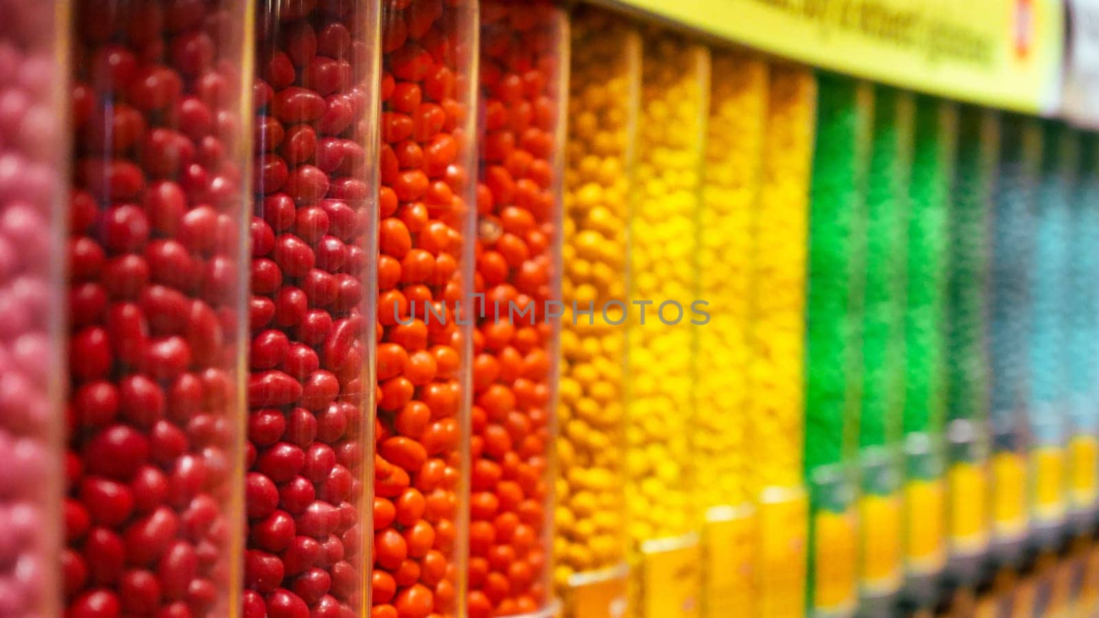 Colorful round candies displayed in clear plastic containers, arranged in a neat row. Perfect for backgrounds or illustrations related to the confectionery industry.