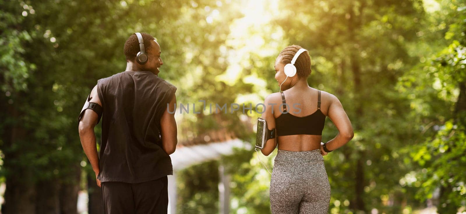 Rear View Of African American Couple Jogging Outdoors In Morning Park, Running On Path Together And Smiling, Enjoying Healthy Lifestyle