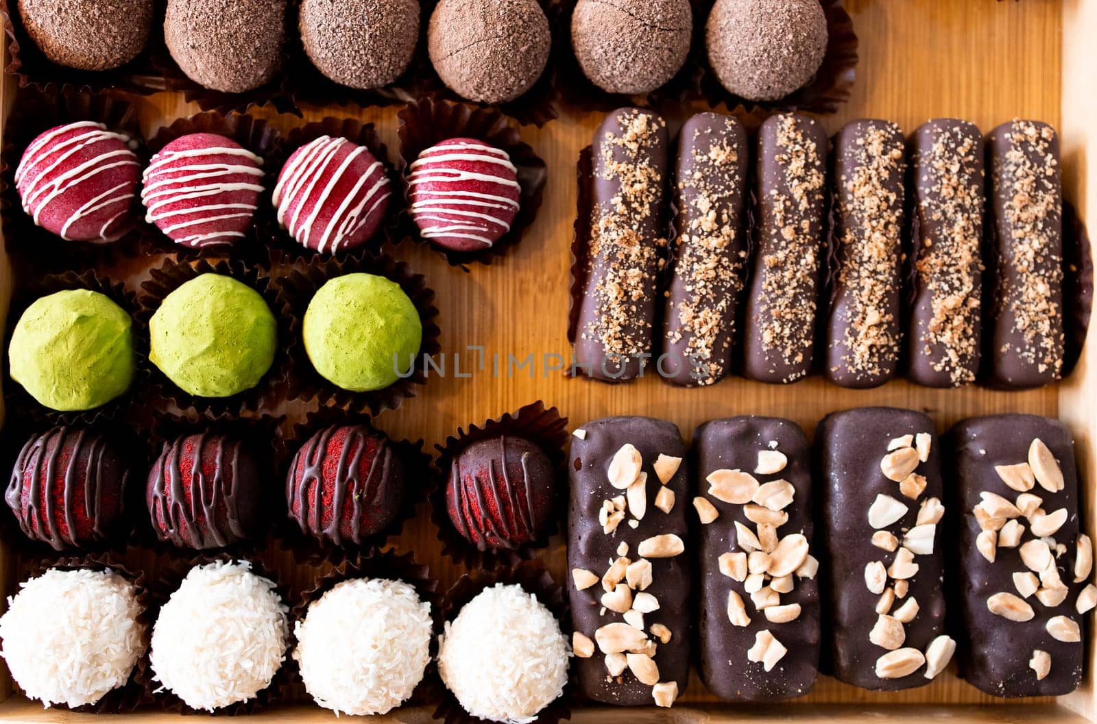Assorted chocolate truffles and bars on a wooden tray with variety of toppings.