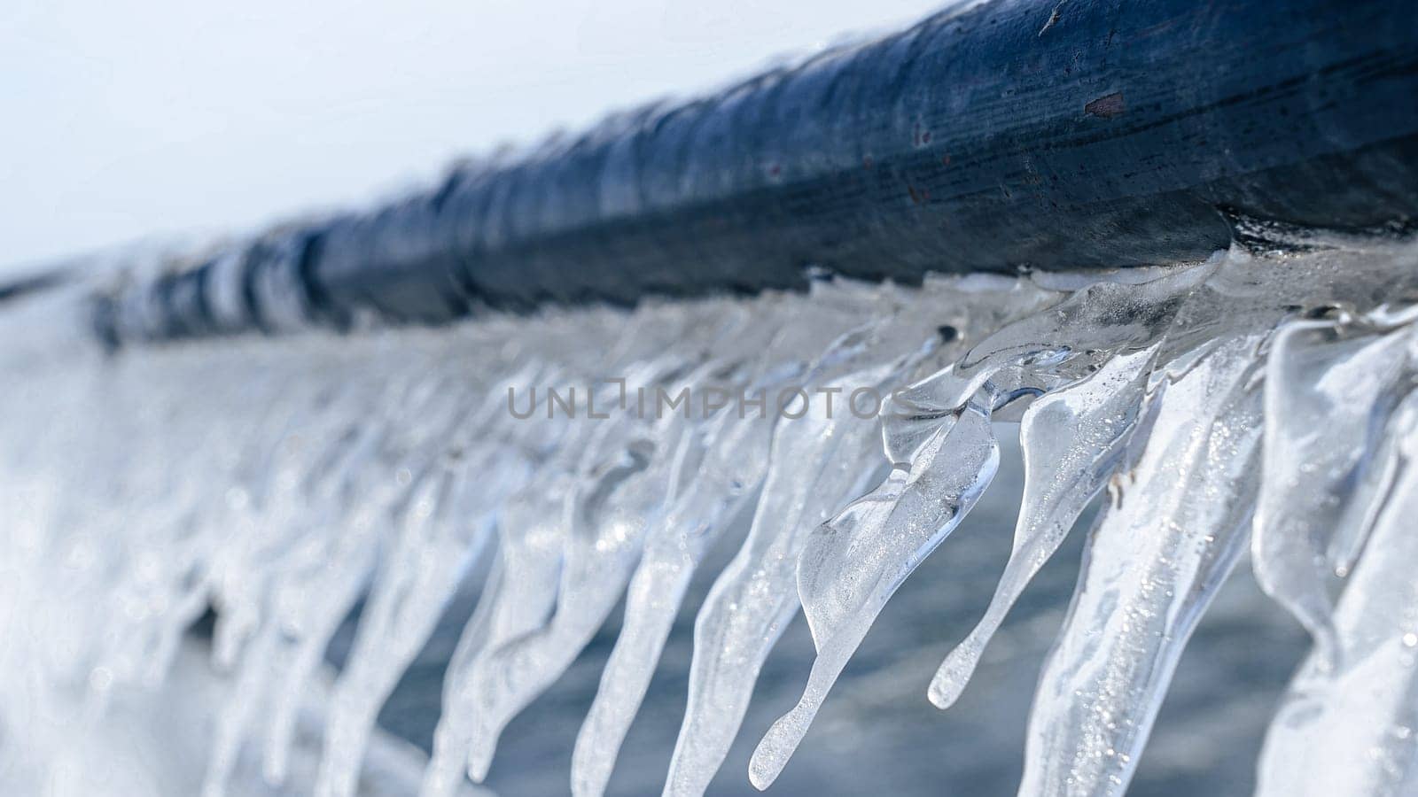 Beautiful Icicles Forming on a Metal Fence with Sunlight Creating a Sparkling Effect in Winter.