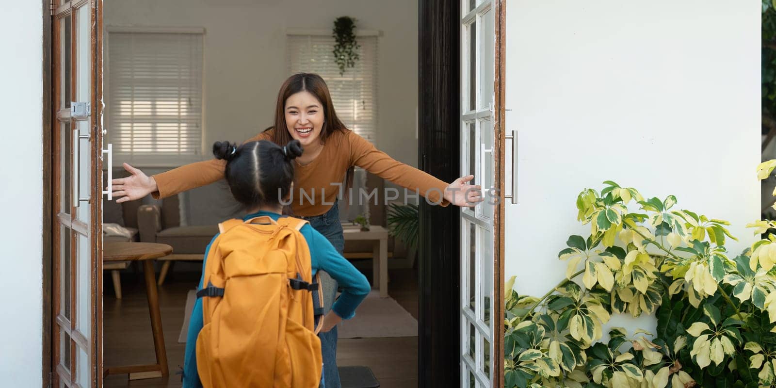 A loving mother greets her daughter with open arms as she prepares to leave for school, encapsulating a moment of love and excitement.