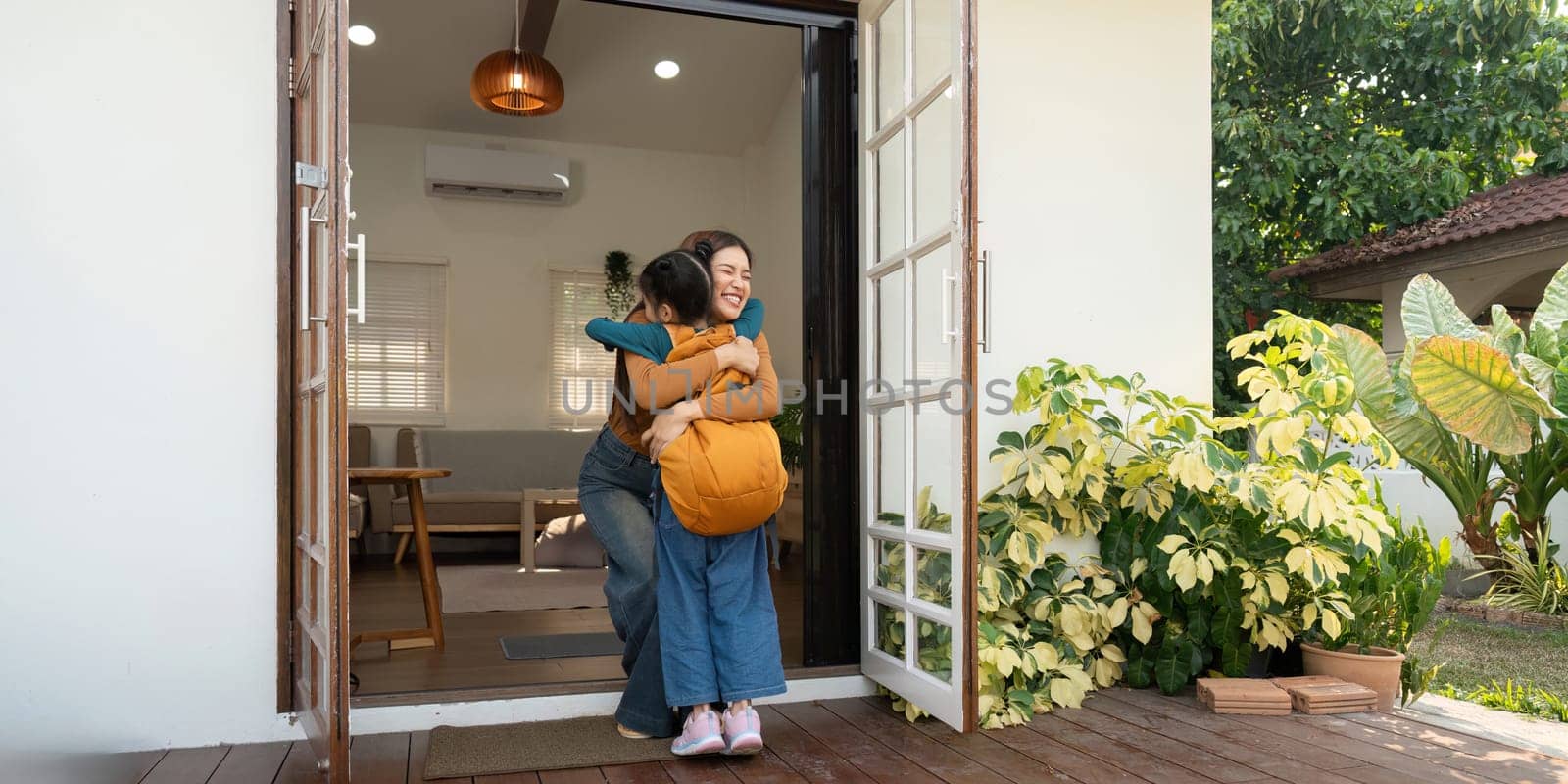 A delighted mother warmly embraces her daughter who just arrived home from school, highlighting the love and connection between them.