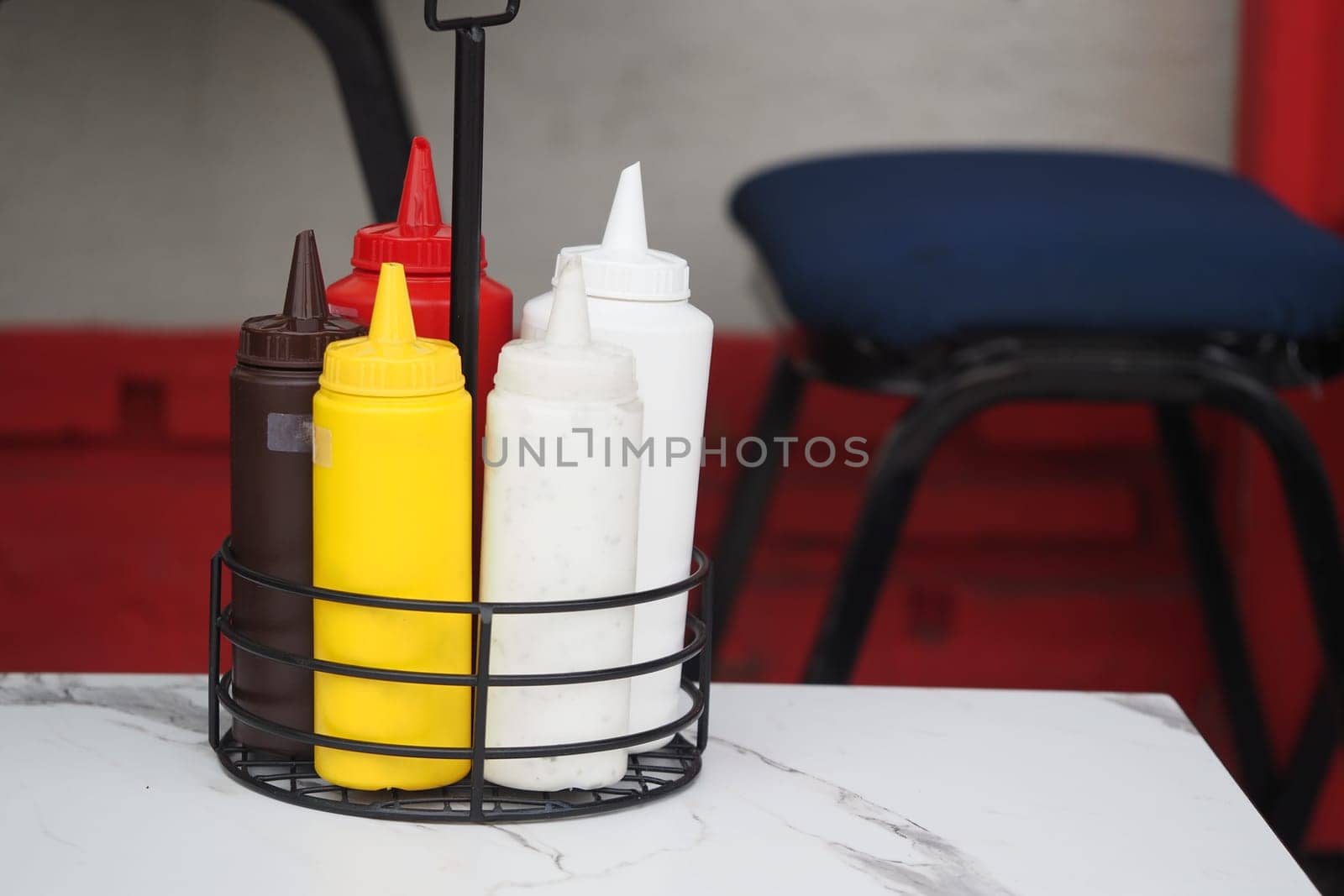 Various condiment bottles sit together on a table at a dining area.